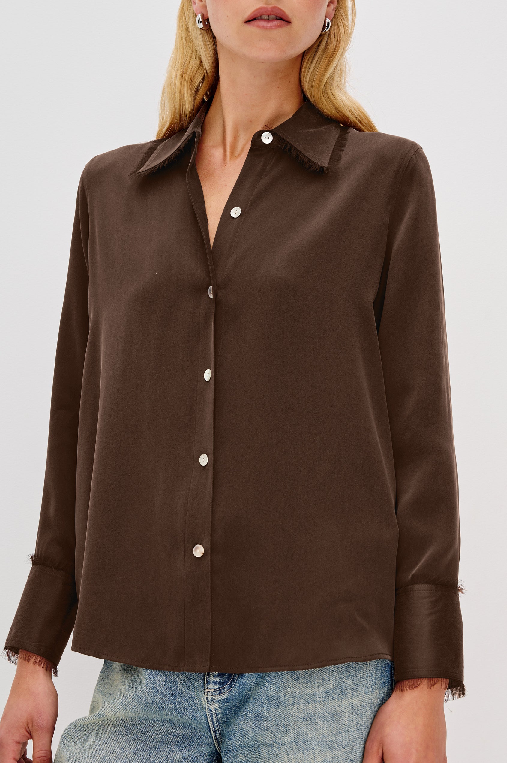 The Abbey is a silk charmeuse button-down shirt with raw edge detailing at the collar and cuffs, with a relaxed fit in Espresso Colorway - Close up of Details on Model