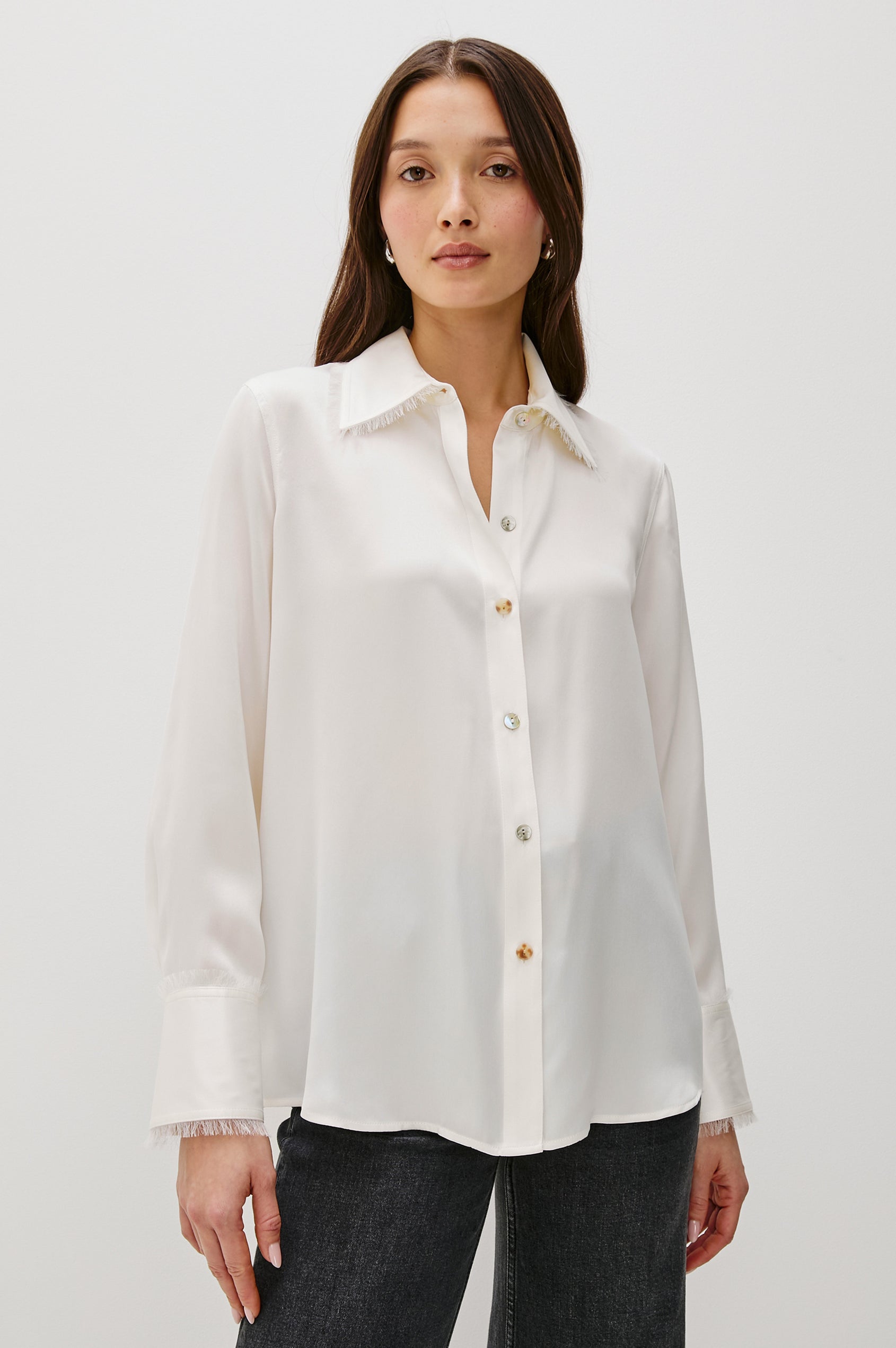 The Abbey is a silk charmeuse button-down shirt with raw edge detailing at the collar and cuffs, with a relaxed fit in Ivory Colorway - Front View Featured on Model, Untucked