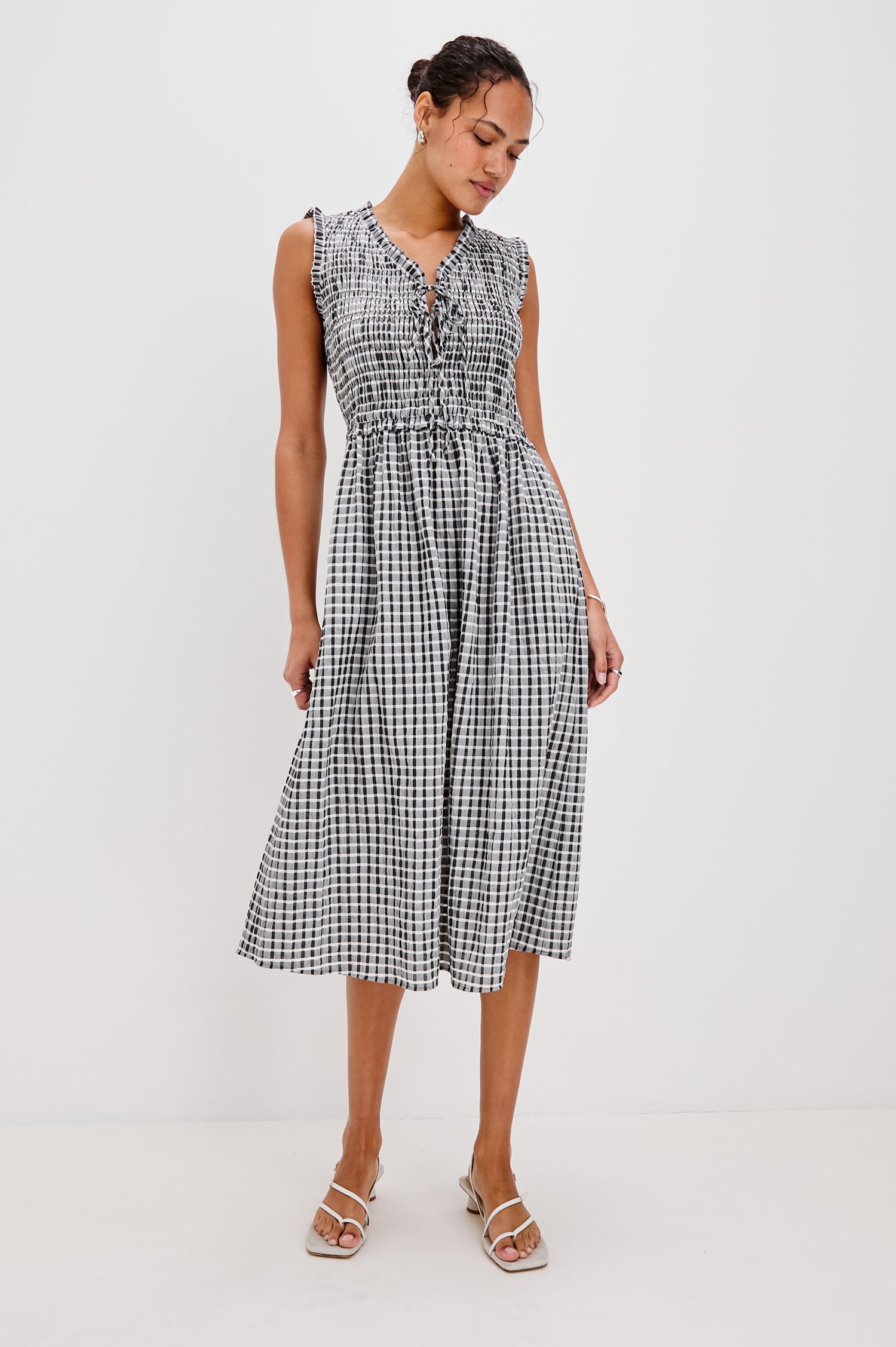 Adine Below-Knee Tank Dress with a Ruffle Edge V-Neck and Armhole, Tie Front, Gathered Bodice and A-Line Skirt in Ash Seersucker Colorway. Full Body Front View Shown on Model.