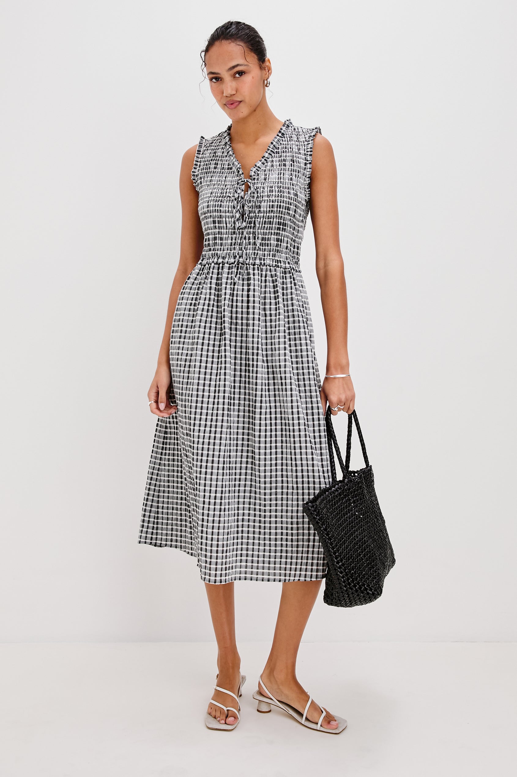 Adine Below-Knee Tank Dress with a Ruffle Edge V-Neck and Armhole, Tie Front, Gathered Bodice and A-Line Skirt in Ash Seersucker Colorway. Full Body Front View Shown on Model.