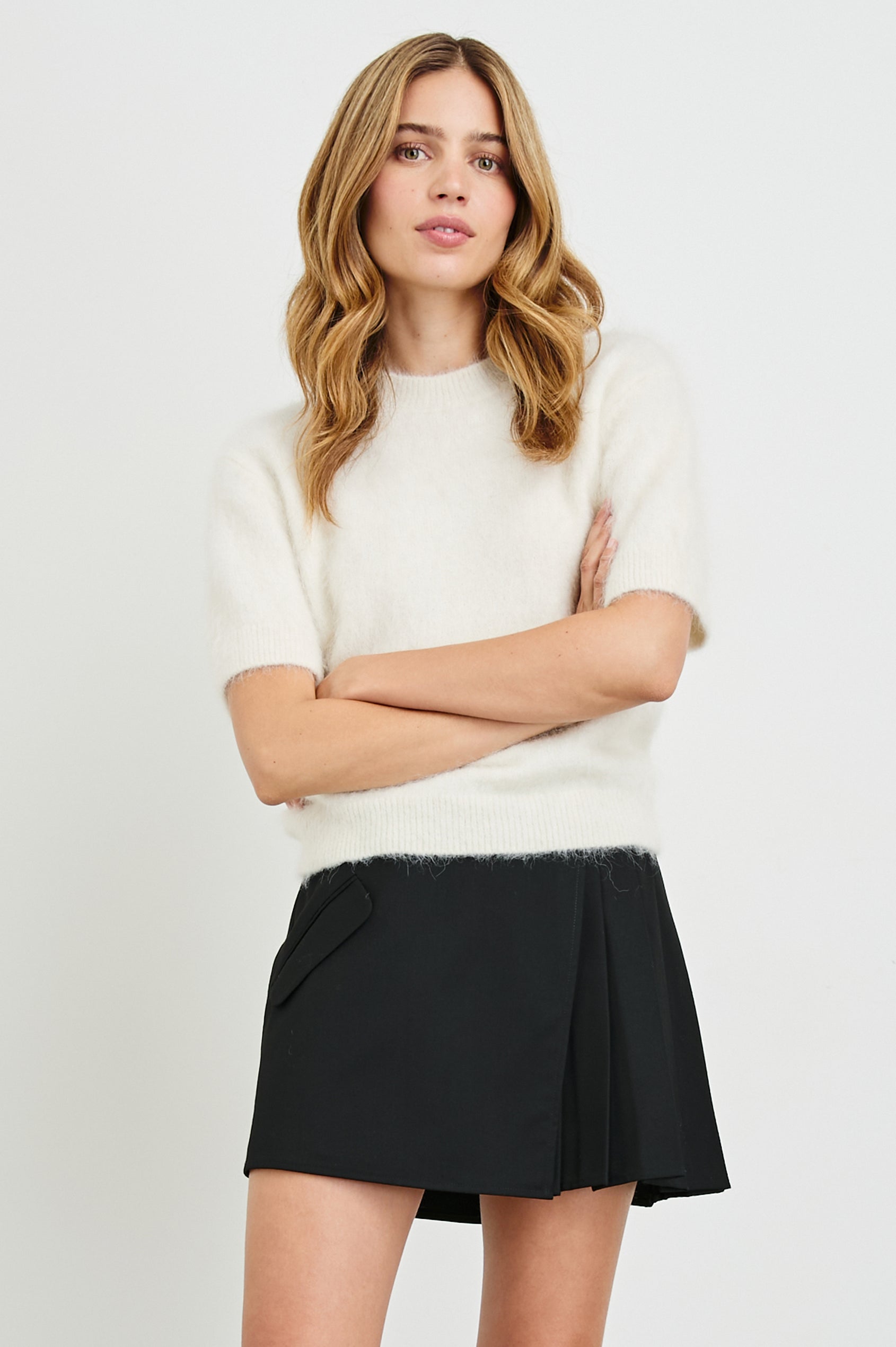 Adriana Mini Wrap Skirt with a Button, Front Flap Pocket and Pleats on Half the Skirt in Black Twill Colorway - Front View Featured on Model 
