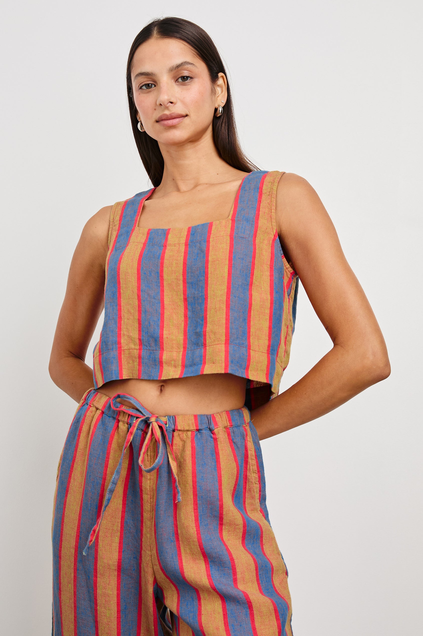 Akira Sleeveless Crop Top with Square Neckline and Wide Shoulder Straps in Rio Stripe Colorway, Vertical Stripes in Tan, Blue, and Pink - Front View Featured on Model 