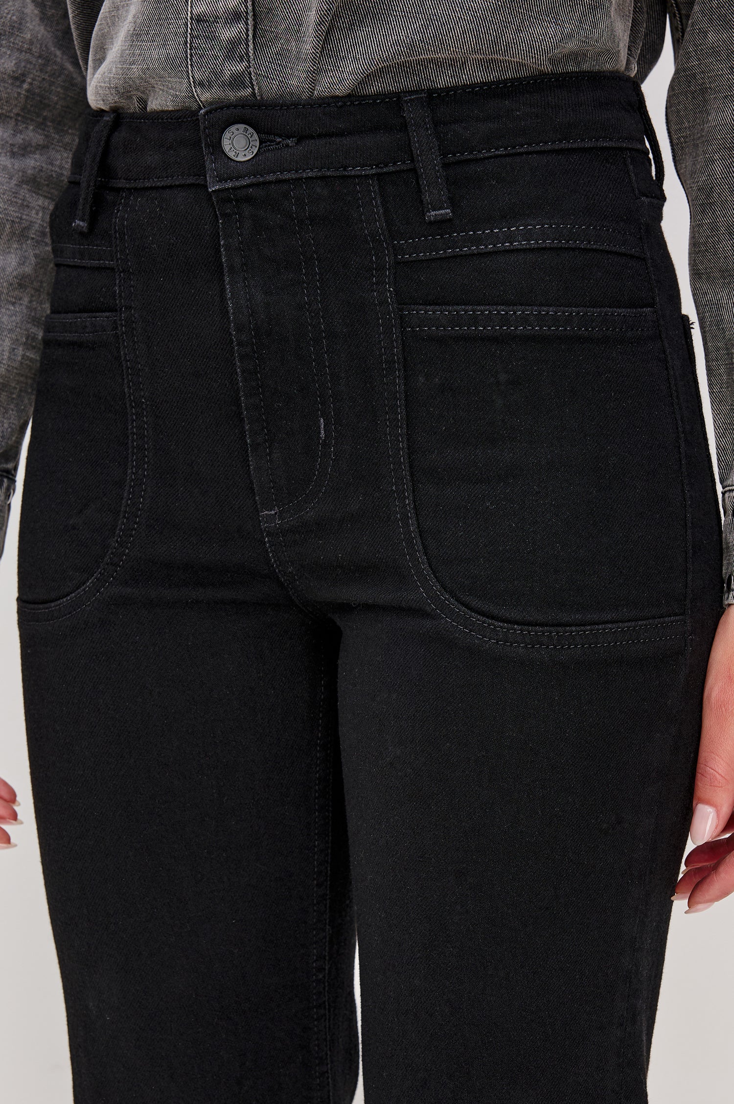 Alamitos is a high waisted denim trouser with flared leg and front patch pockets in Blackout colorway. Front detail view on model.
