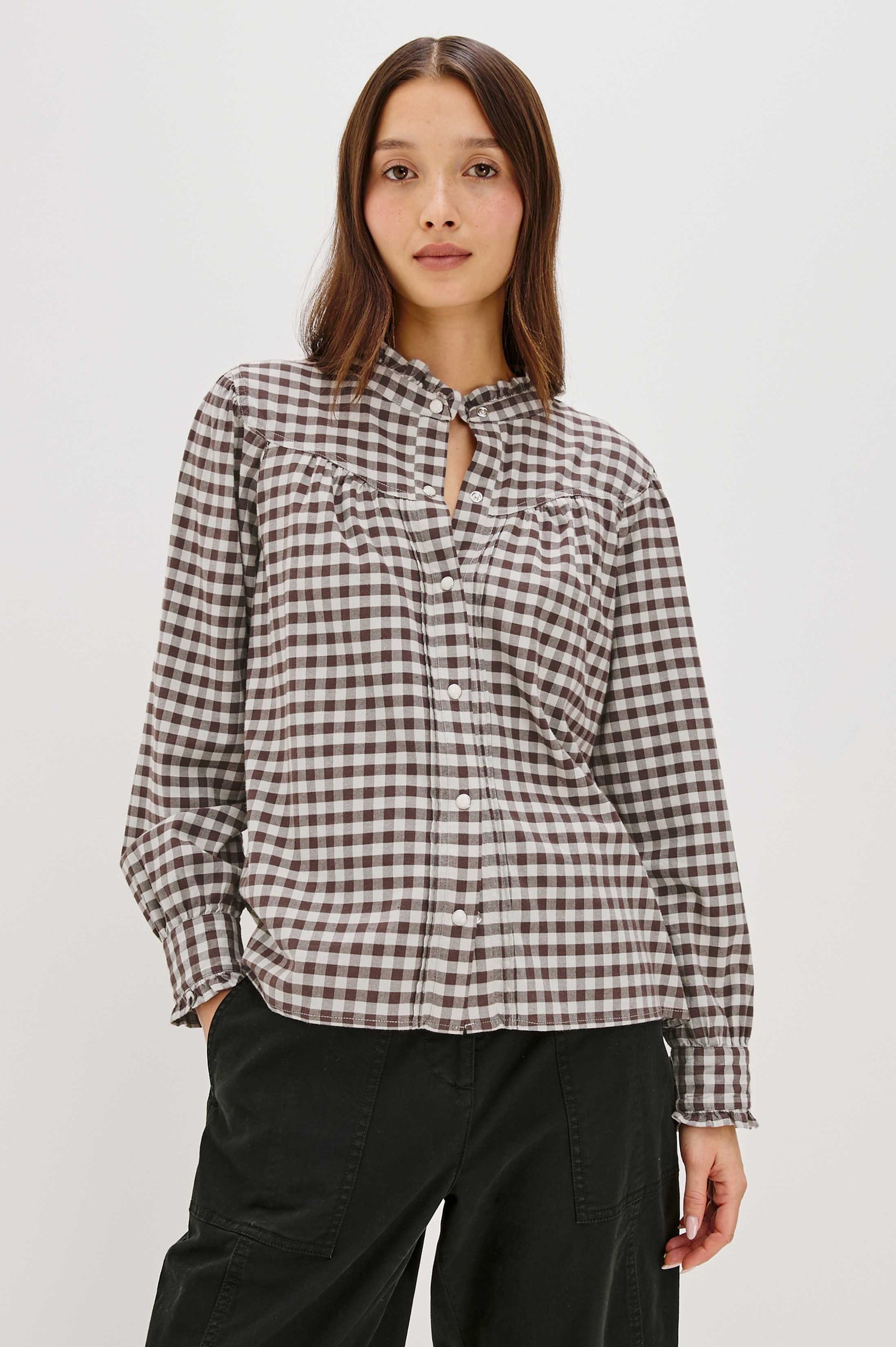 Woman wearing a checkered shirt and black pants on a white background