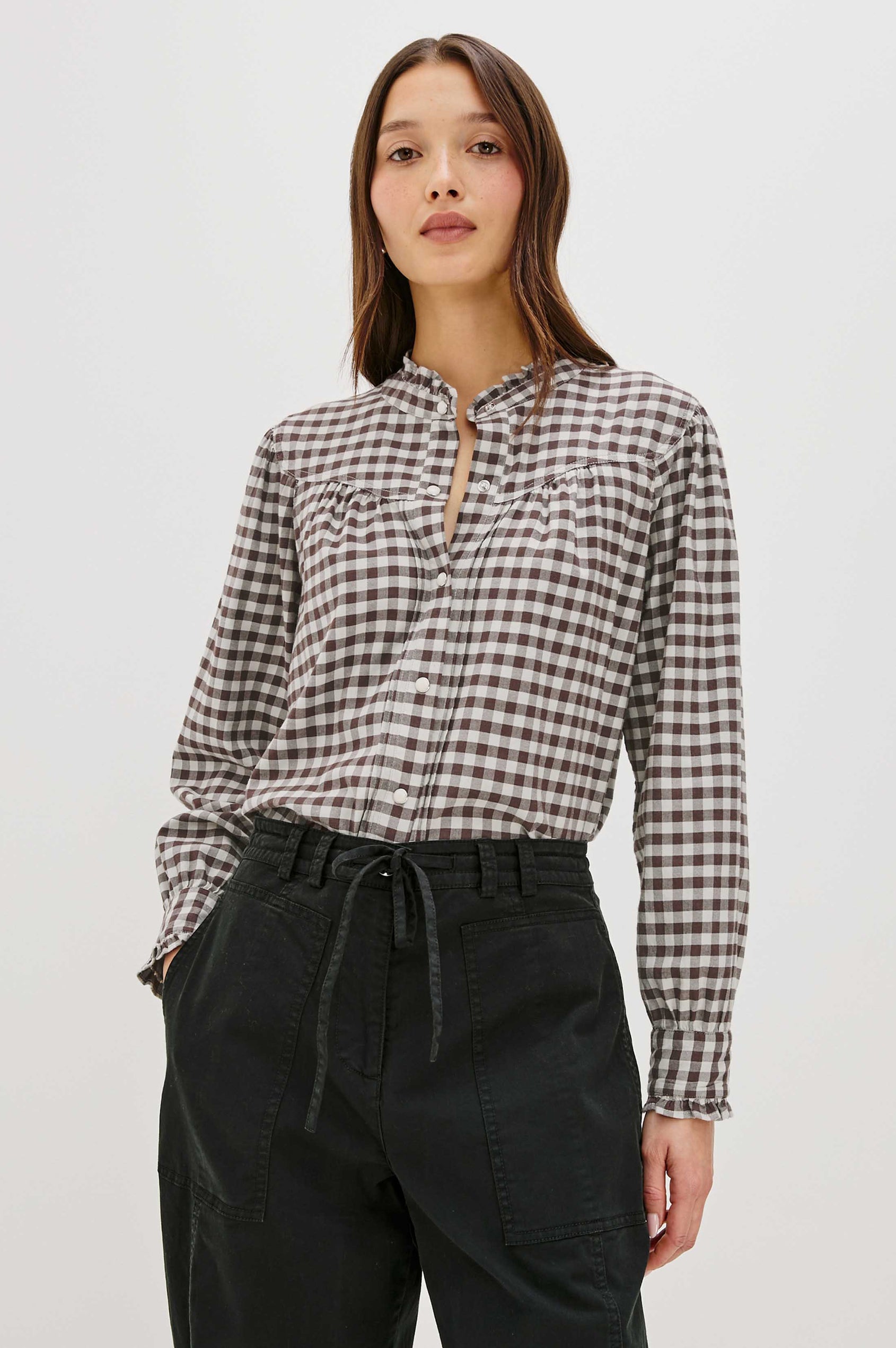 Woman wearing a checkered shirt and black pants on a white background