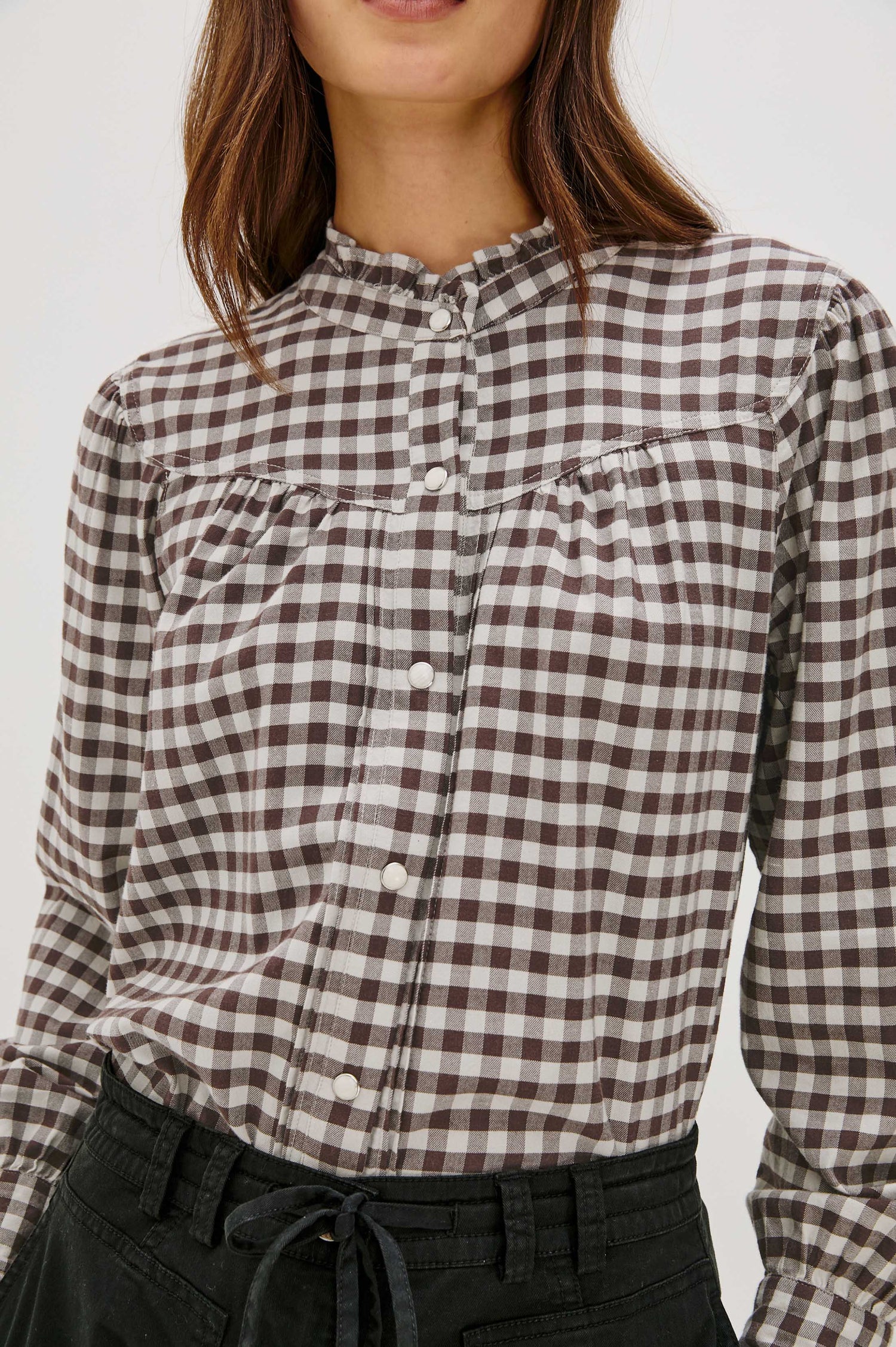 Woman wearing a brown and white checkered shirt on a white background
