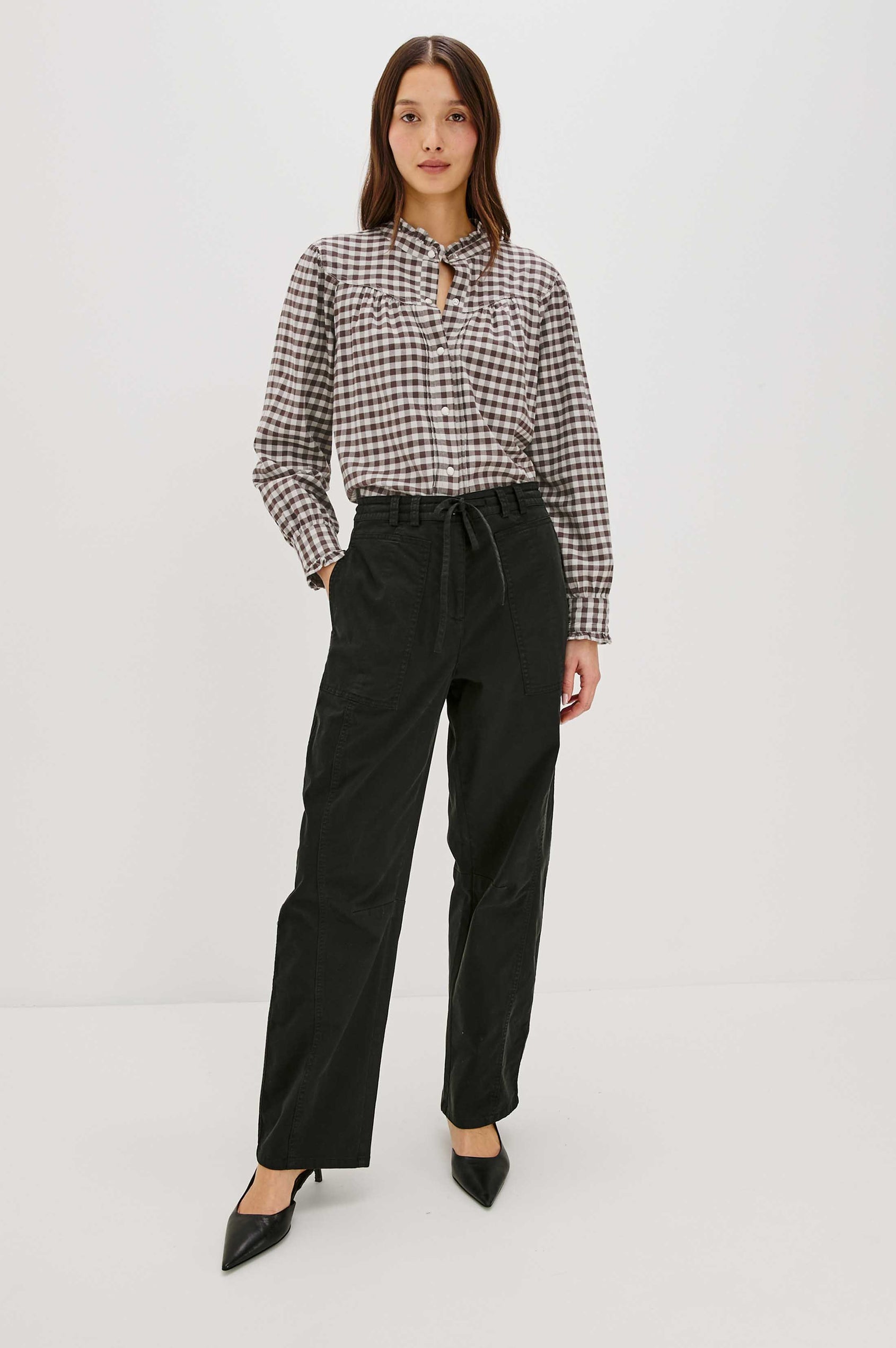 Woman wearing a checkered blouse and black pants on a white background