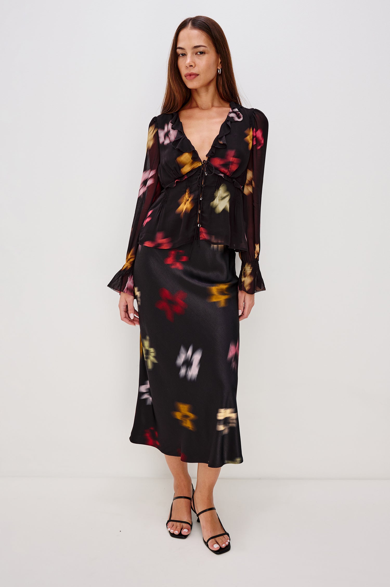 Alixa Blouse in Chiffon With Ruffled Deep V-Neckline, Front Buttons, and Long Balloon Sleeves With Smocked Bell Cuffs in Blurred Floral Colorway - Full Body Front View Featured on Model