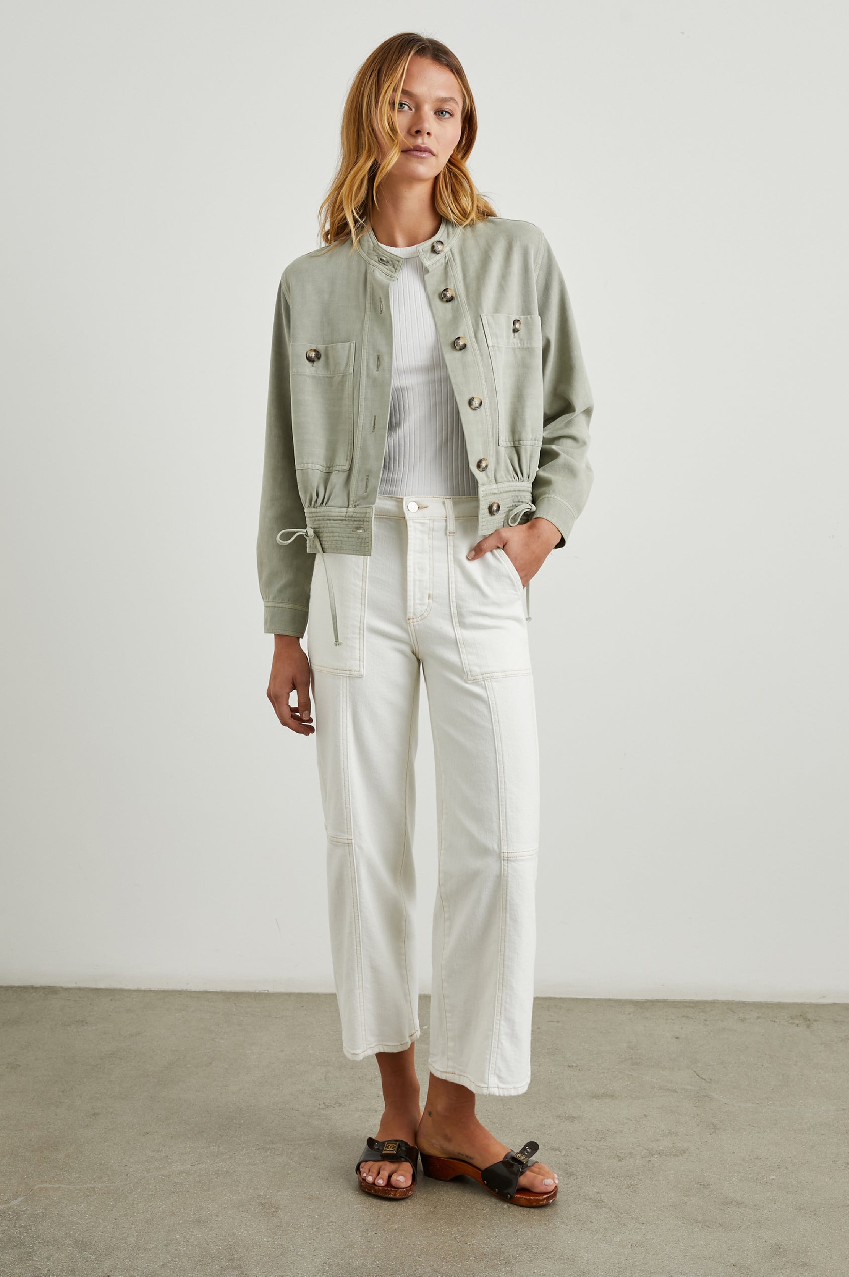 Alma Jacket with Button Closure, Mandarin Collar, Two Large Chest Button Patch Pockets and a Drawcord at the Hem in Sage Colorway - Front Full Body View Featured on Model