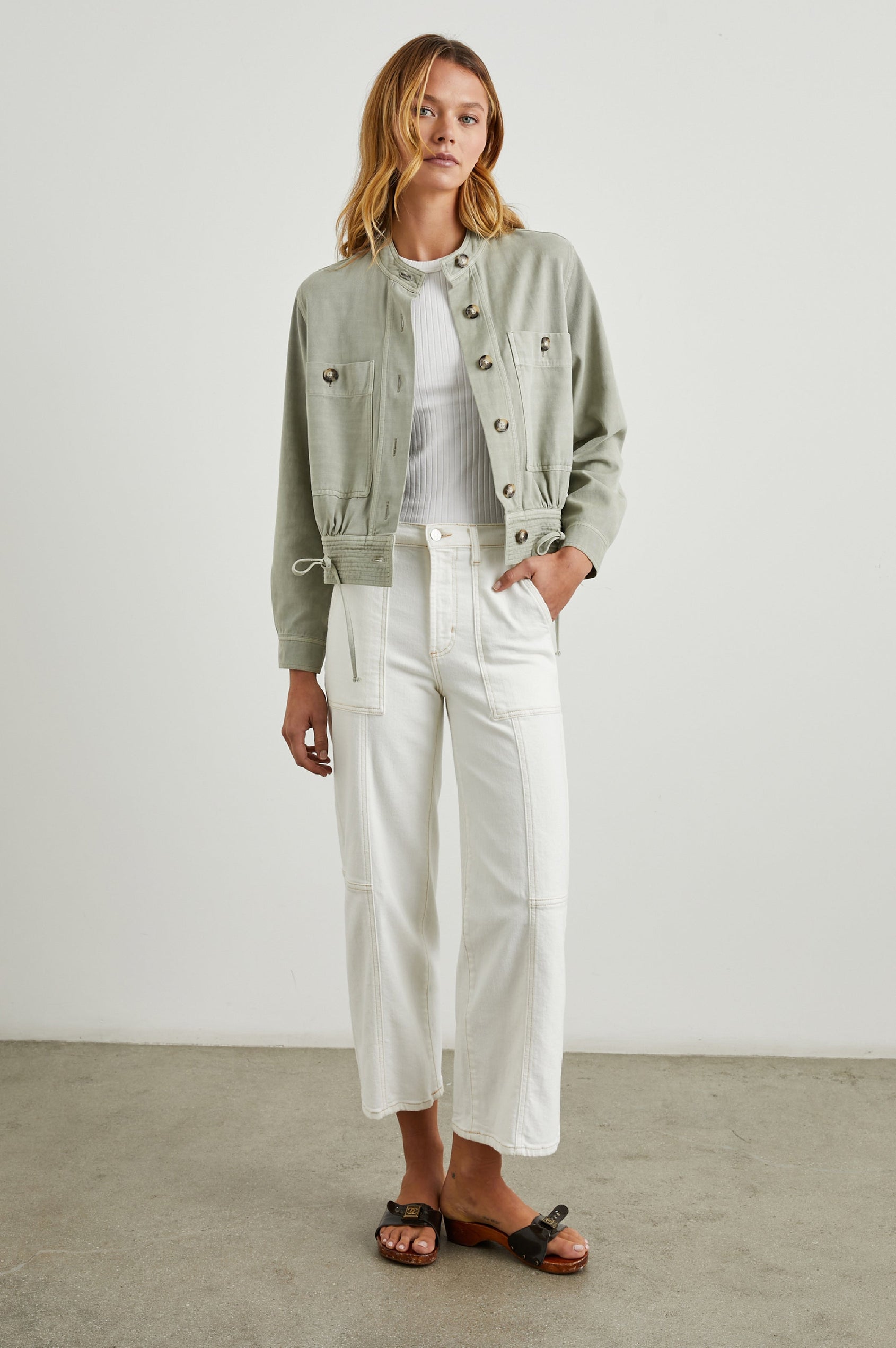 Alma Jacket with Button Closure, Mandarin Collar, Two Large Chest Button Patch Pockets and a Drawcord at the Hem in Sage Colorway - Front Full Body View Featured on Model