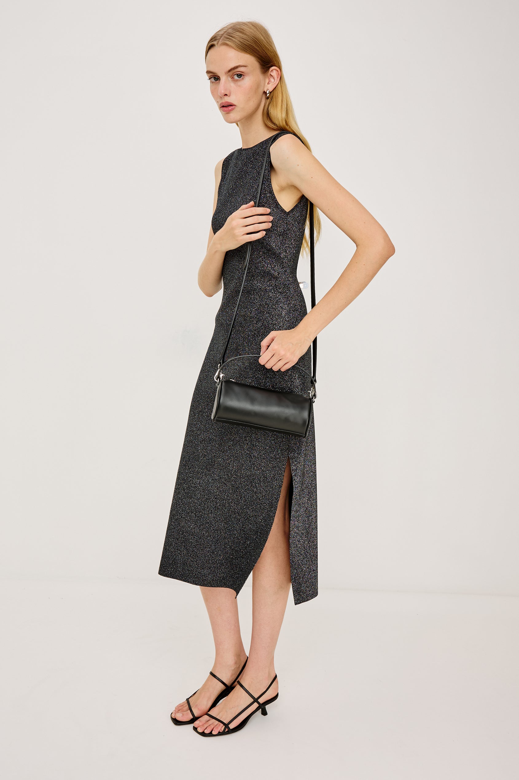 Alora Sleeveless Midi Dress in Fine Ribbed Knit With a Boat Neck and a Mid-Thigh Side Slit in Gunmetal Lurex Colorway - Full Body Side View Featured on Model Sitting