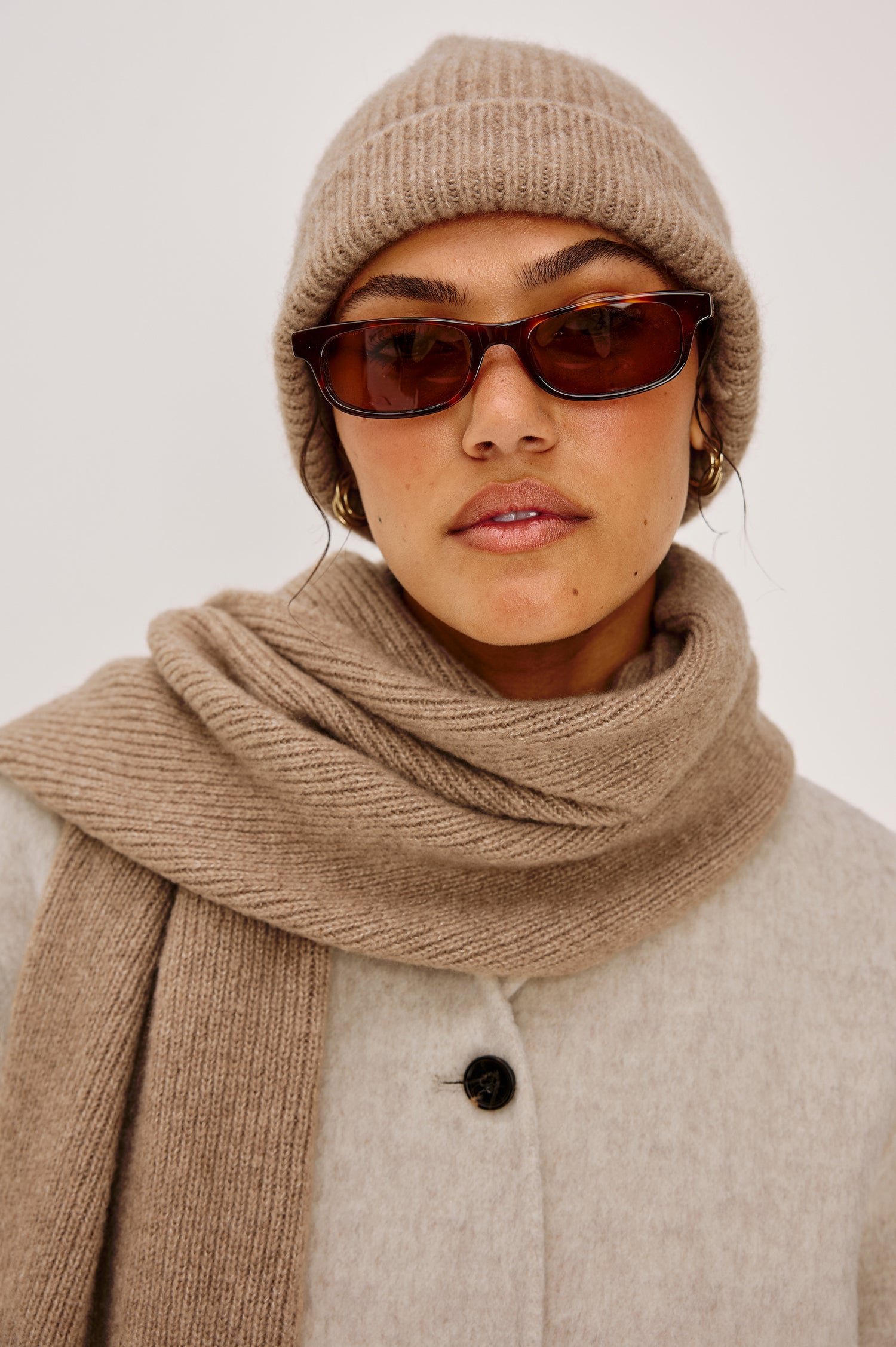 Alps is a cashmere scarf in Oat colorway. Front detail view featured on model.