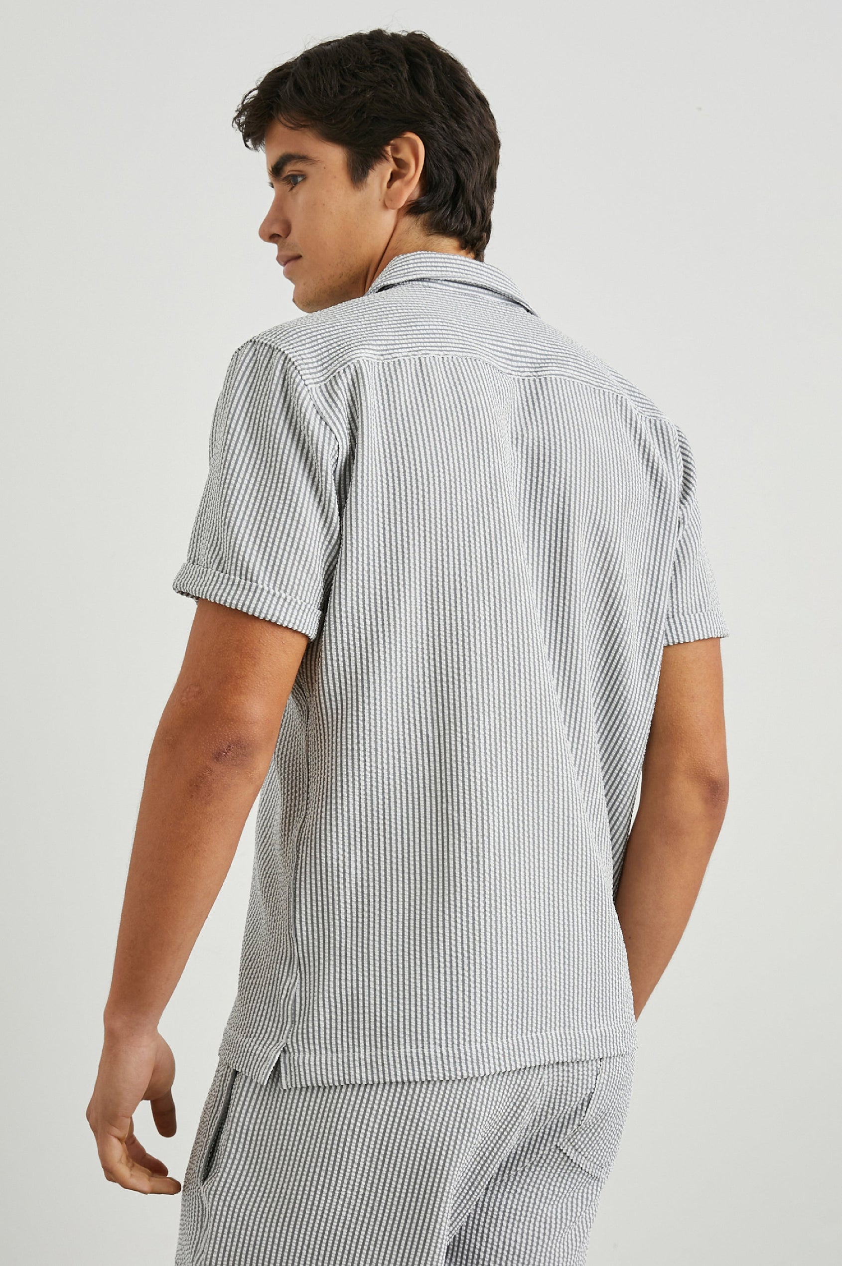 Amalfi Short-Sleeve Button Up in Faded Seersucker Colorway, Grey and white thin vertical stripes  - Back View Featured on Model