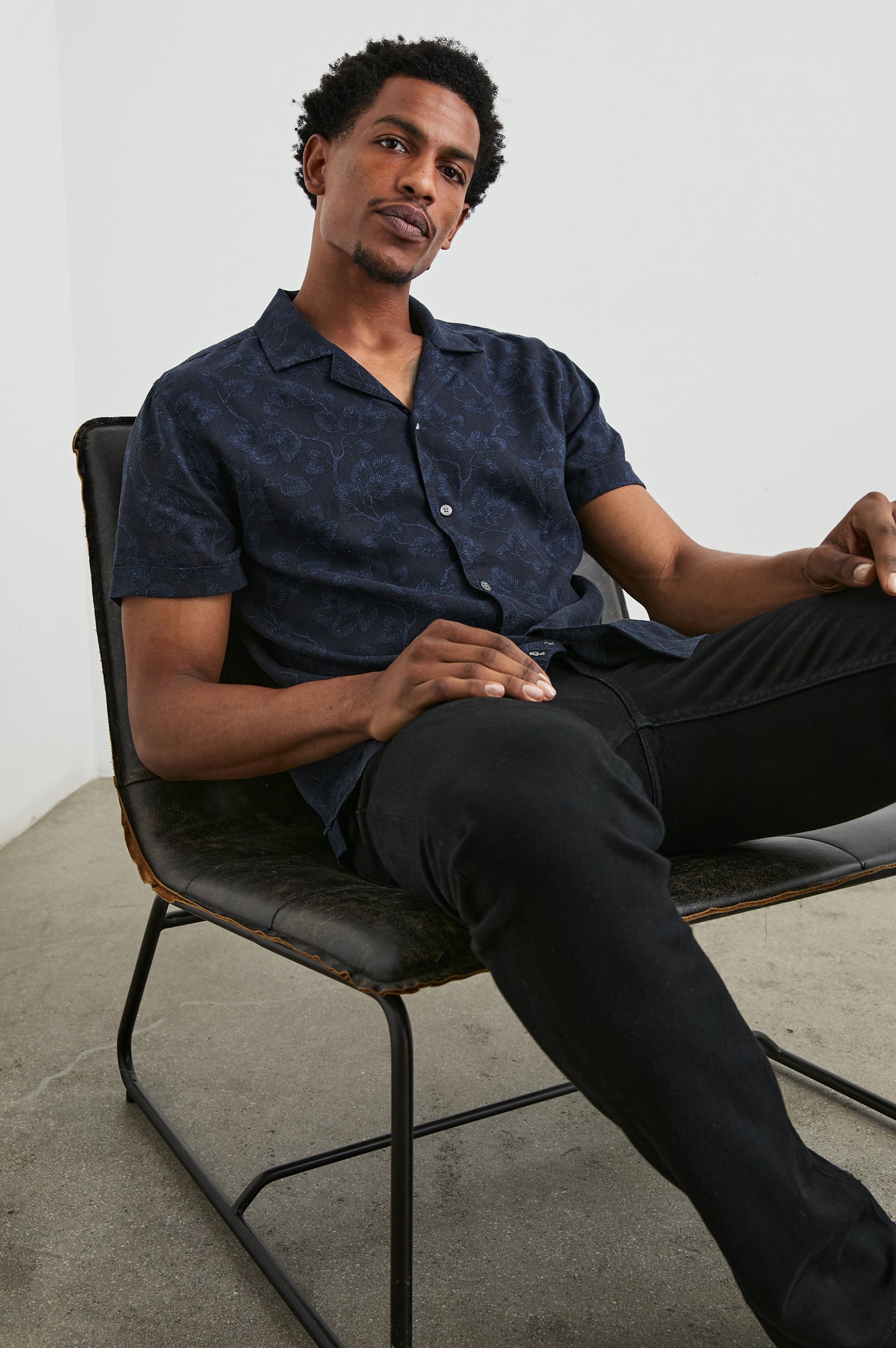 Amalfi Short-Sleeve Button Up in Japanese Maple Indigo Colorway, Indigo leaves on Black  - Front View Featured on Seated Model