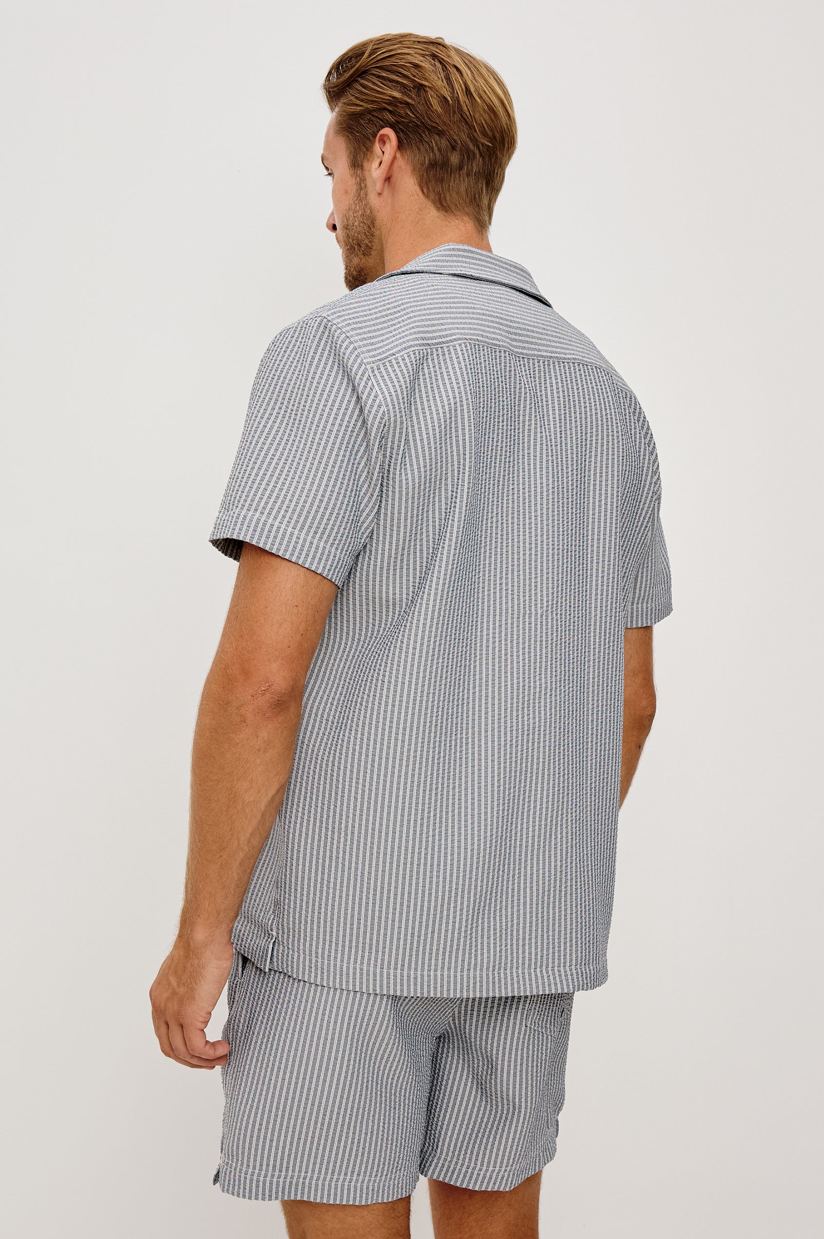 The Amalfi Button-Up Short Sleeve Shirt in Lightweight Stretch Linen-Blend With a Notched Collar and Classic Fit in Navy Deck Stripe - Upper Body Back View Featured on Model