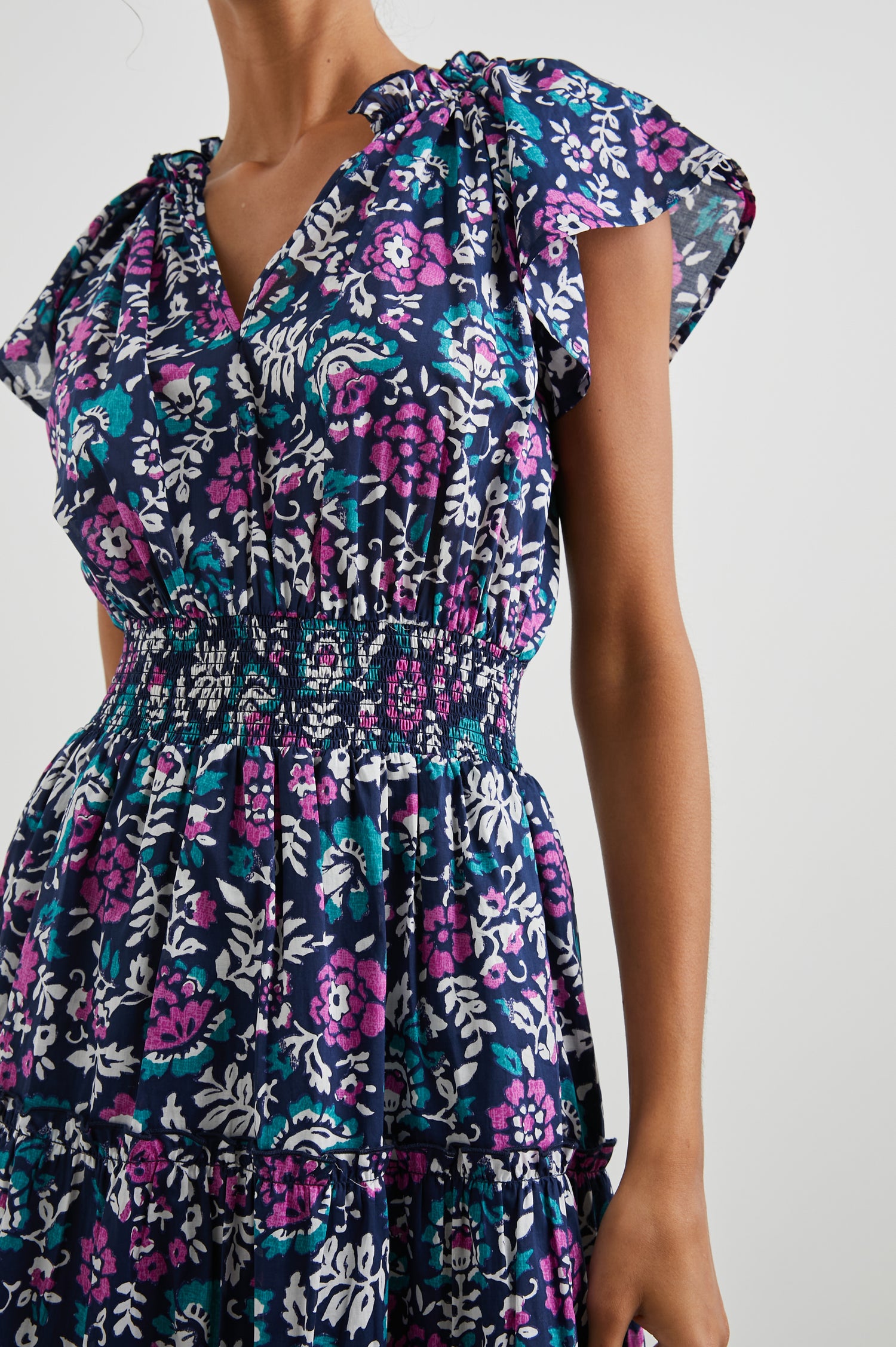 Amellia Short-Sleeve Midi Dress with Smocked Waist and Collar, V Neck, and a Tiered Skirt in Woodblock Floral Colorway, Flowers in Purples, Greens and White on Navy - Front View Featured on Model