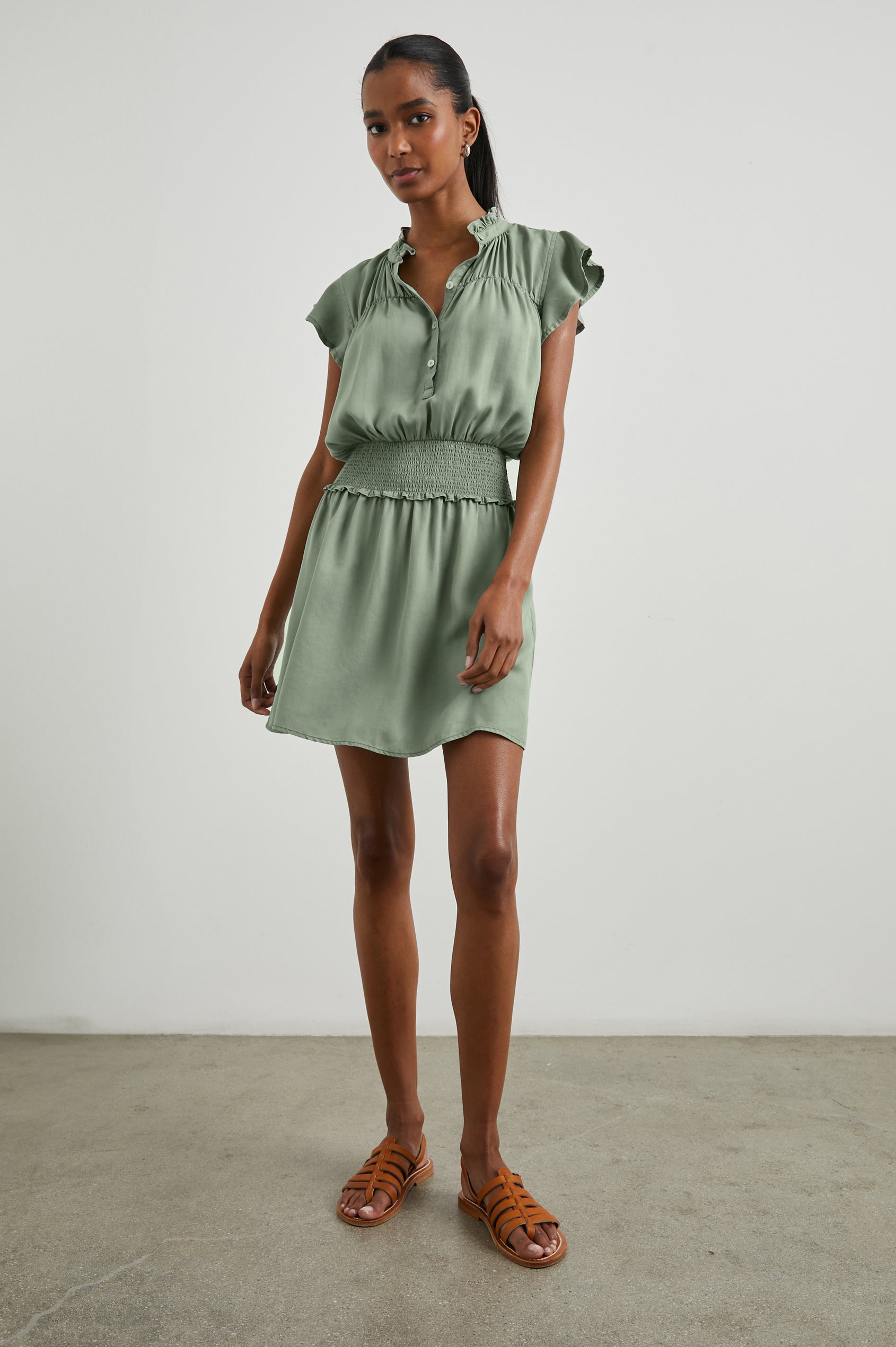 Amina Short Sleeve Mini Dress with Flutter Sleeves, a Ruffled Collar with Ruching, a Button Placket, and a Shirred Waist in Sage Denim Colorway - Front Full Body View Featured on Model 