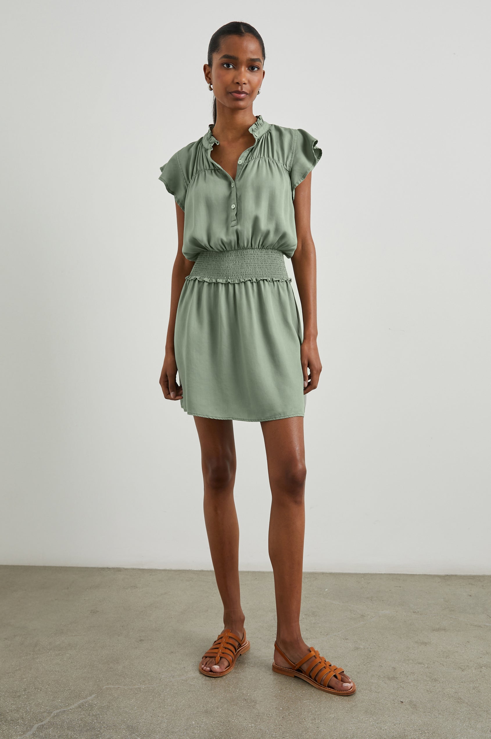 Amina Short Sleeve Mini Dress with Flutter Sleeves, a Ruffled Collar with Ruching, a Button Placket, and a Shirred Waist in Sage Denim Colorway - Front Full Body View Featured on Model 