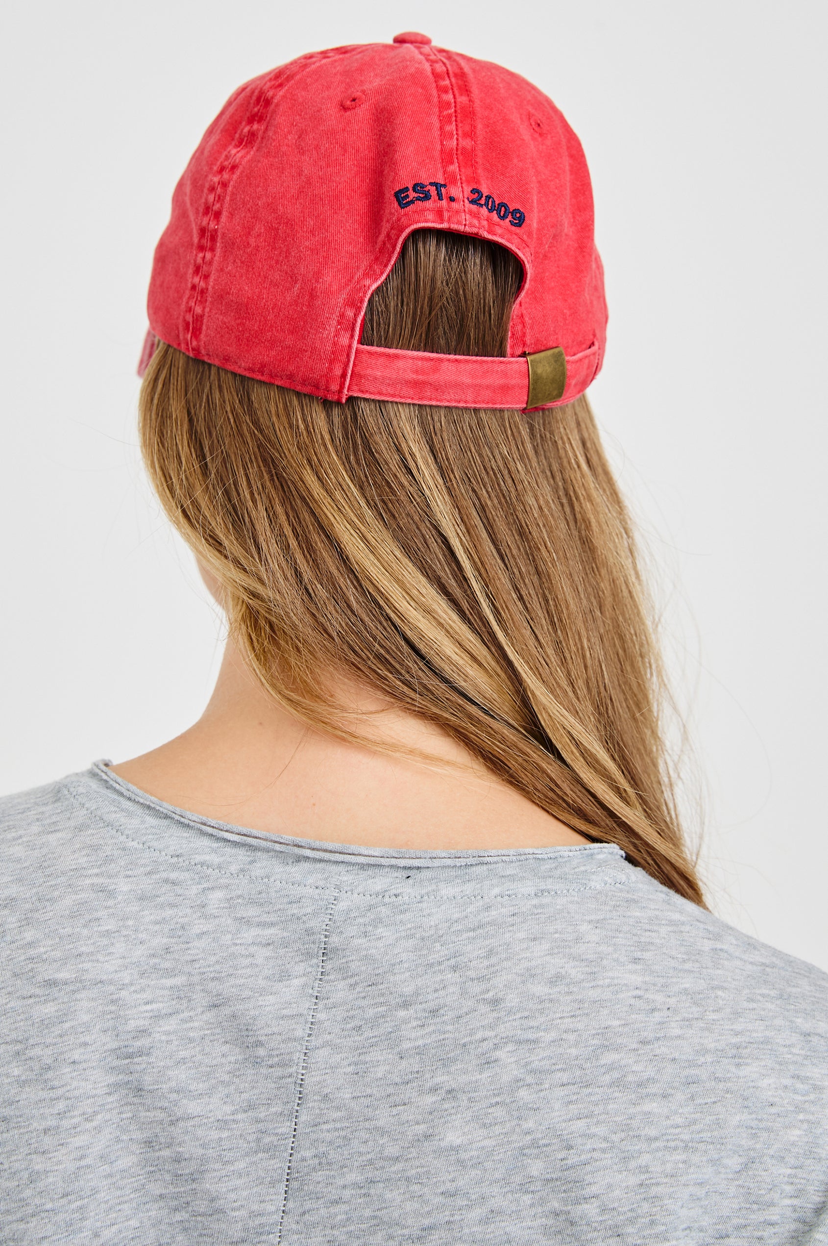 Anniversary Baseball Cap with an Adjustable Back Strap, Front Text, Rails, and Back Text, Est 2009, in Washed Red Colorway, with Blue Text - Back View Featured on Model