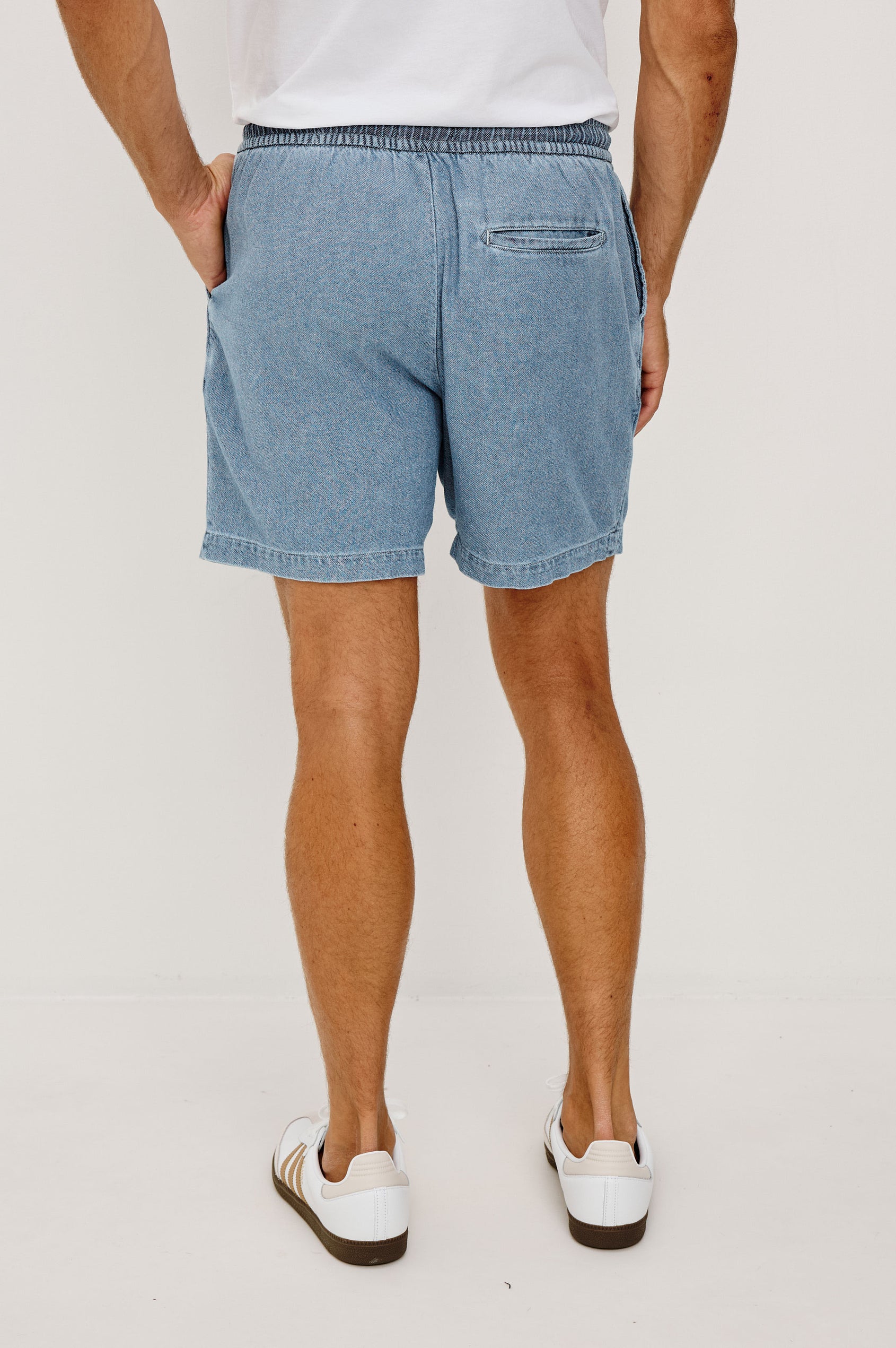 Archer Short in Unlined Cotton Linen With Relaxed Fit, Adjustable Waist Drawstring Ties, Side Pockts, and 6-Inch Inseam in Medium Wash Indigo Colorway - Back View Featured on Model