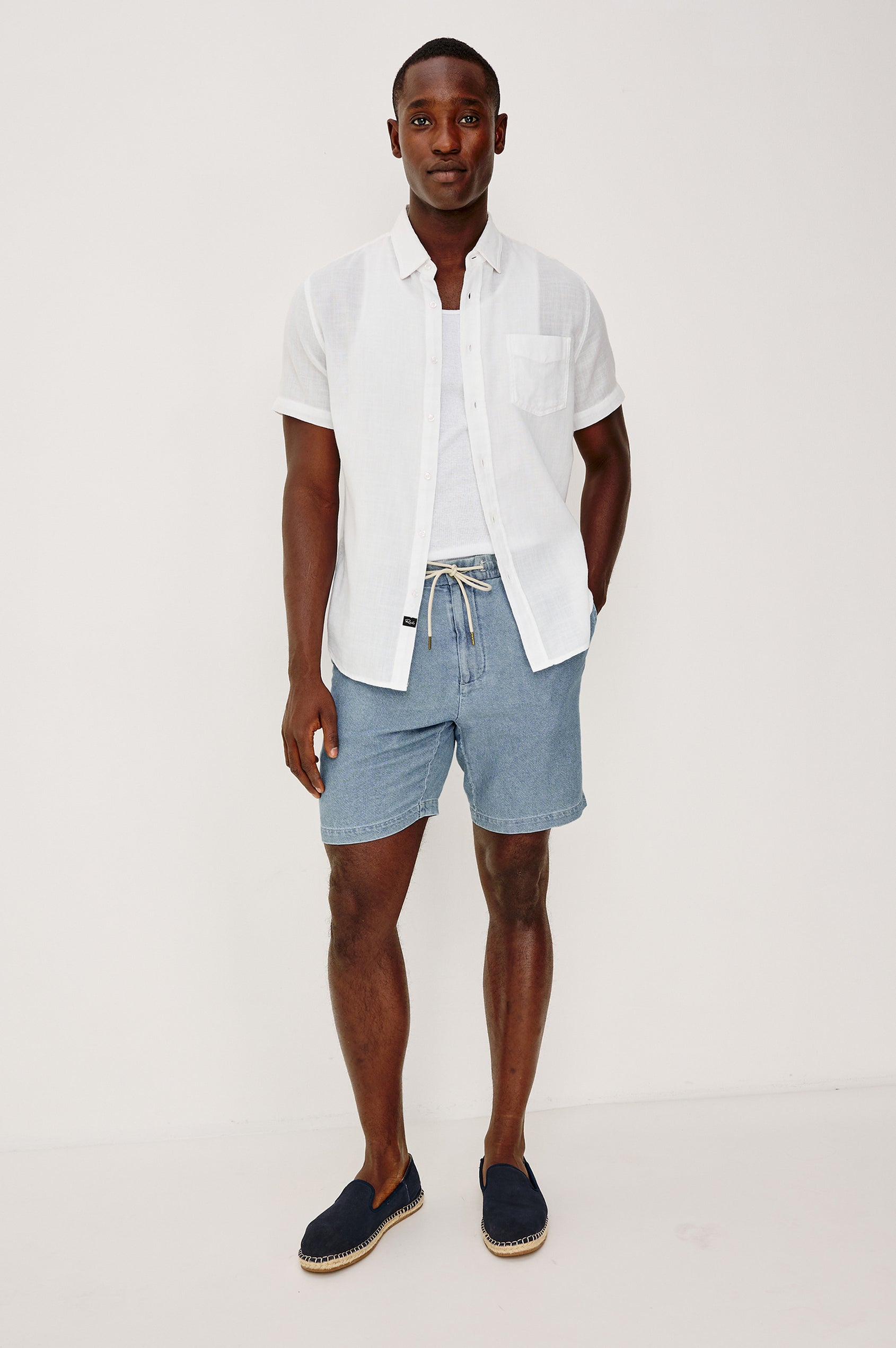 Archer Short in Unlined Cotton Linen With Relaxed Fit, Adjustable Waist Drawstring Ties, Side Pockts, and 8.5-Inch Inseam in Medium Wash Indigo Colorway - Full Body Front View Featured on Model