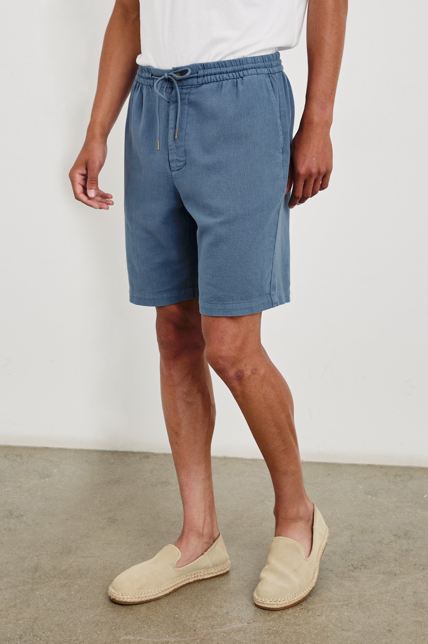 Archer long length cotton short with adjustable drawstring and front button closure in Washed Blue - front view on model, slight angle in motion.