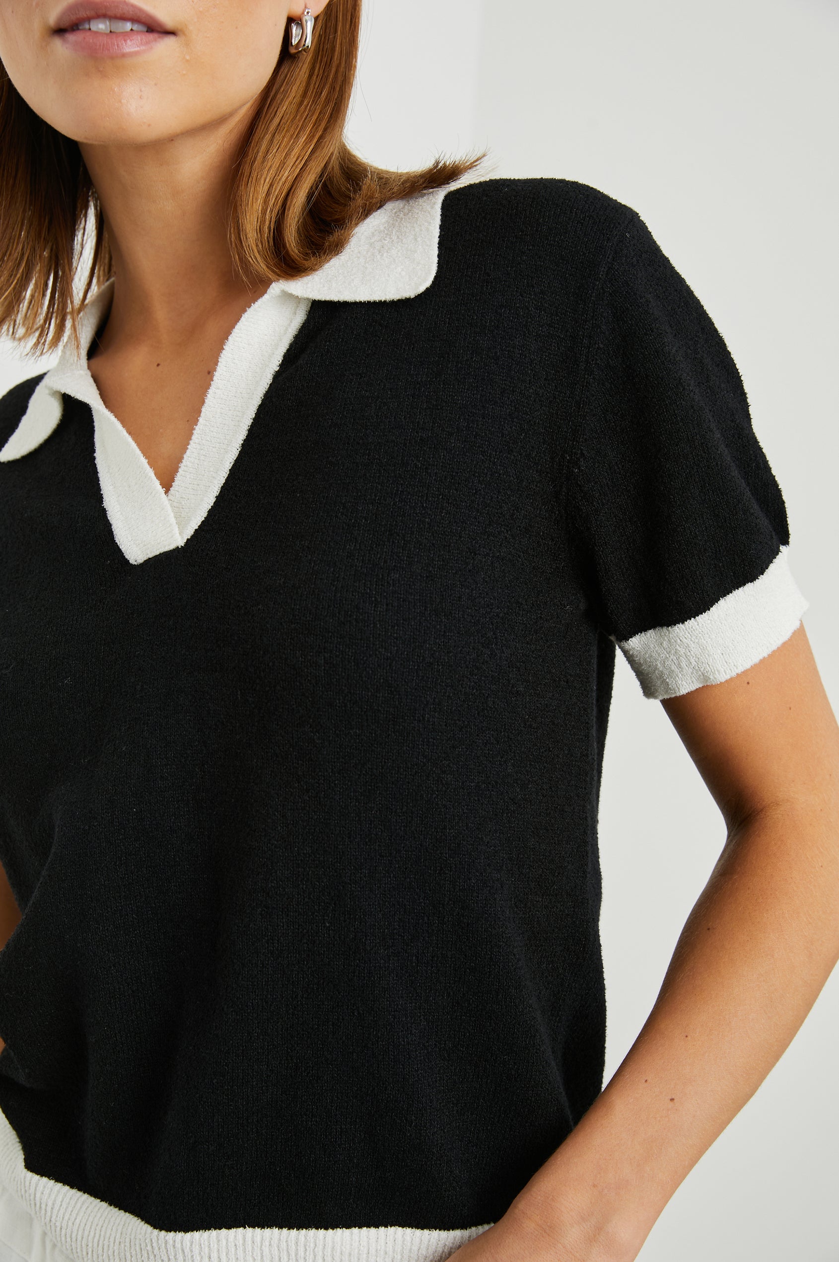 Arya Short Sleeve Top with a V Neck and Collar in Black Colorway, with White Trim - Front View Featured on Model 