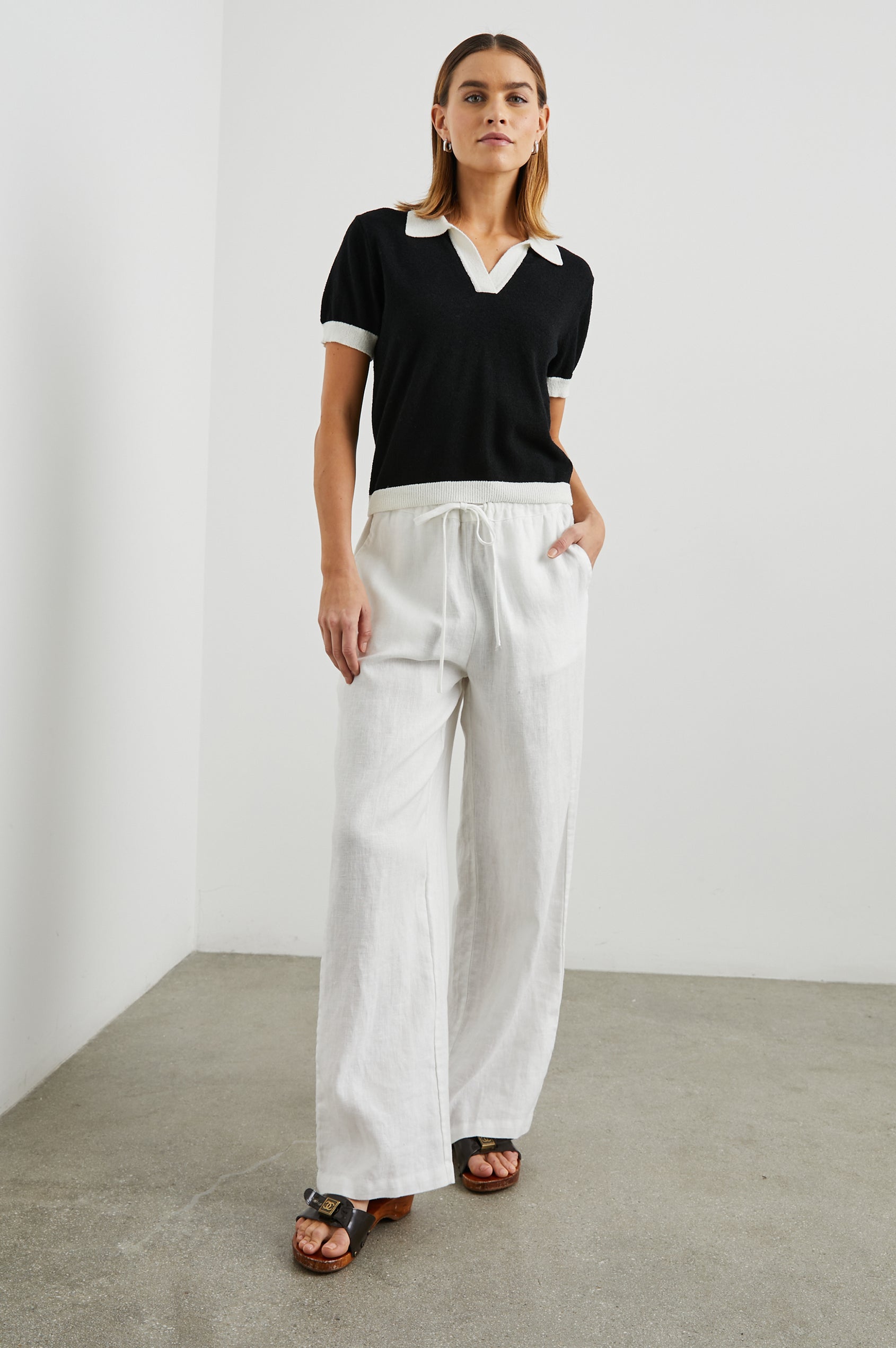 Arya Short Sleeve Top with a V Neck and Collar in Black Colorway, with White Trim - Front Full Body View Featured on Model 
