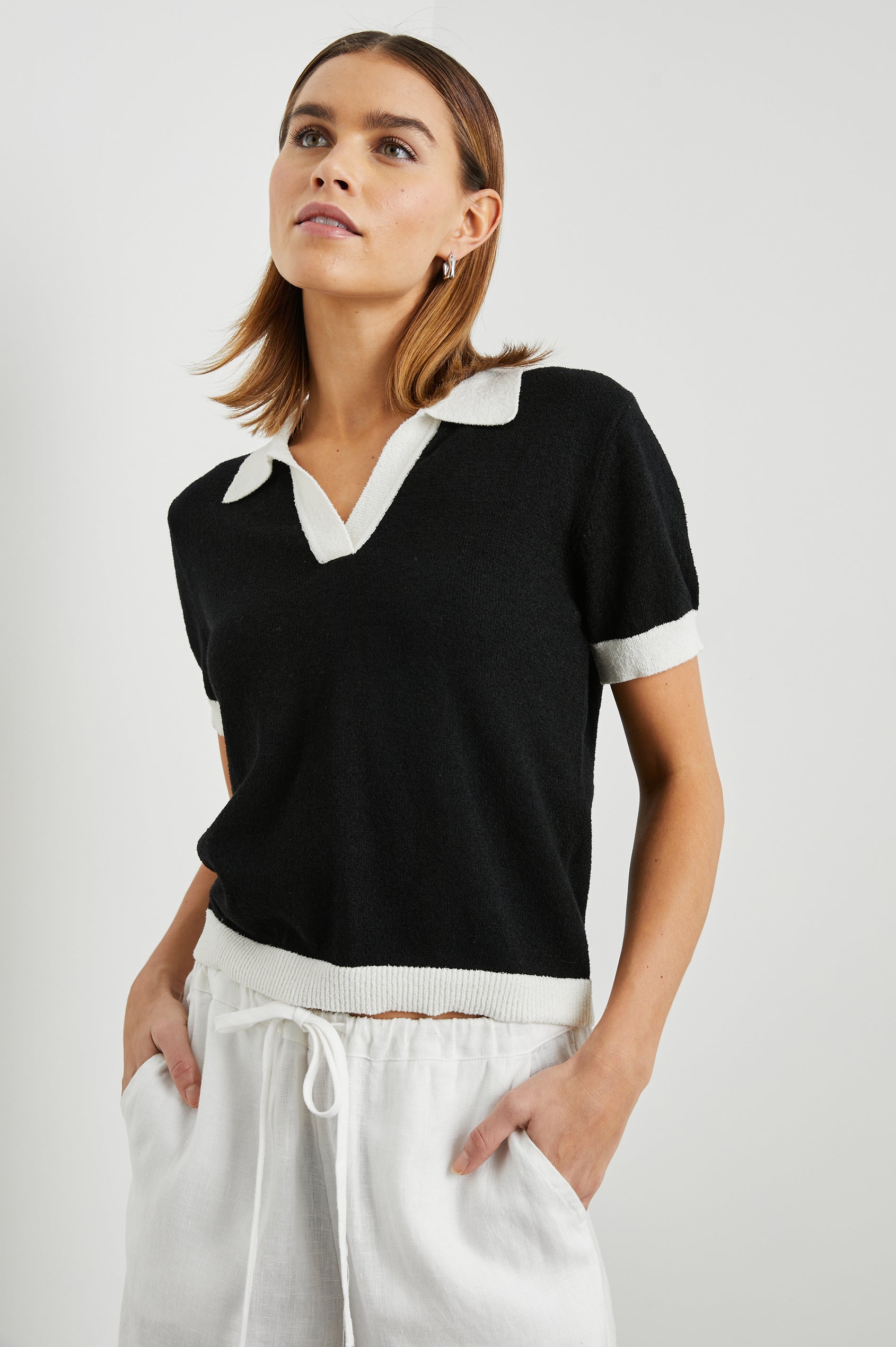 Arya Short Sleeve Top with a V Neck and Collar in Black Colorway, with White Trim - Front View Featured on Model 