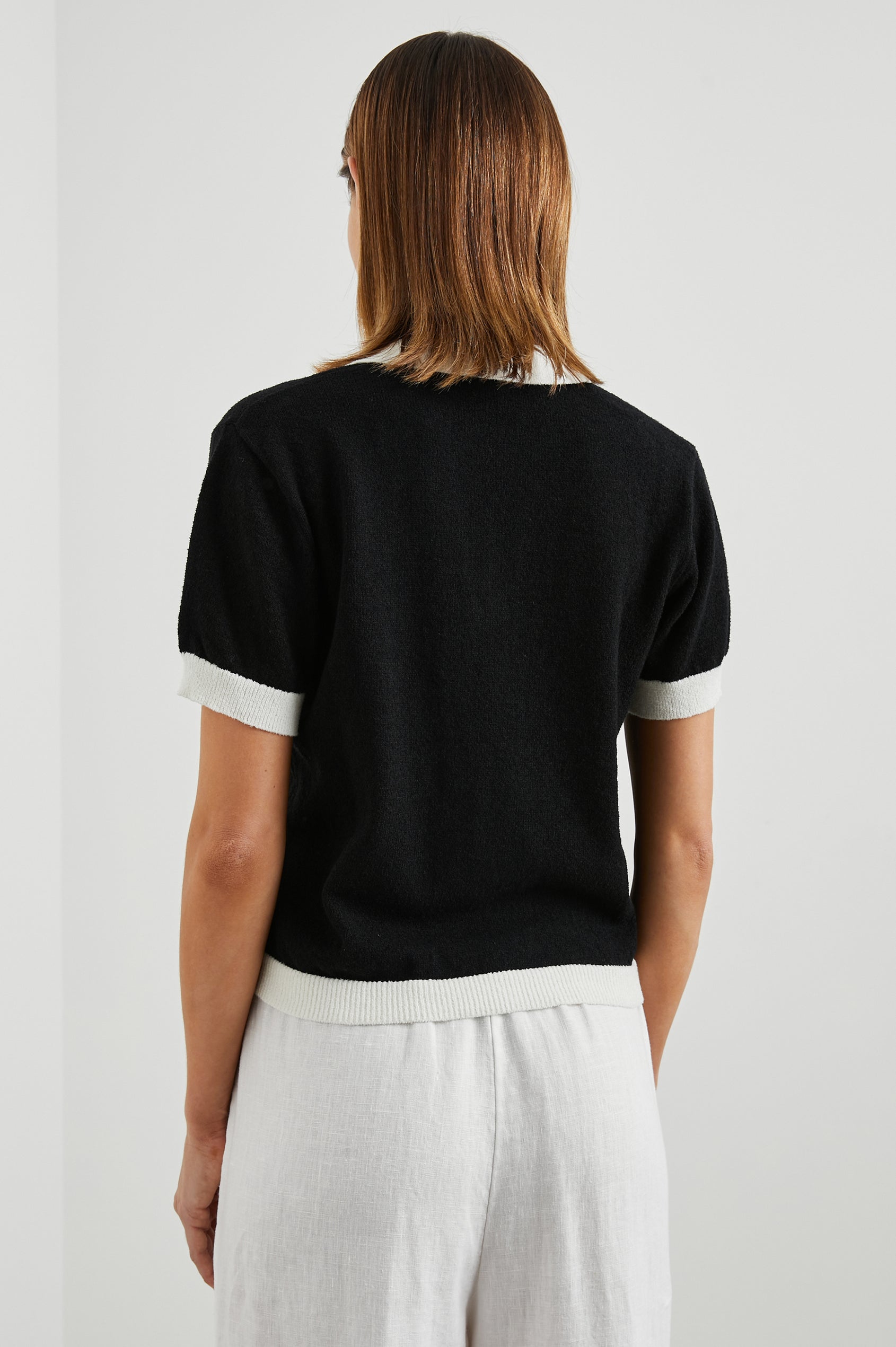 Arya Short Sleeve Top with a V Neck and Collar in Black Colorway, with White Trim - Back View Featured on Model 