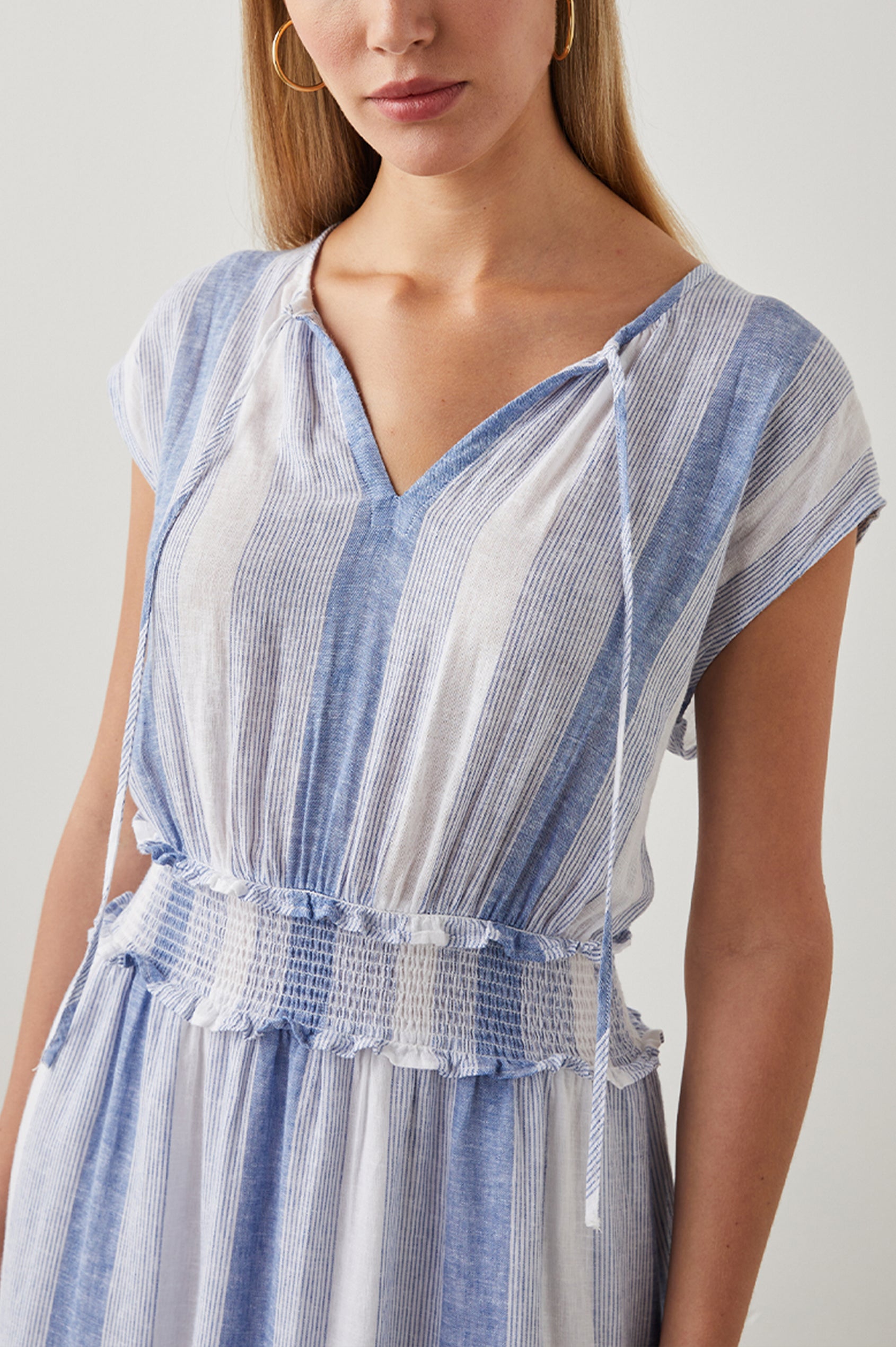 Ashlyn Short Sleeve Midi Dress with a V neck with Ties, a Smocked Waist and a Ruffle Tier at the Hem in Nevis Stripe Colorway, Vertical Stripes in Blue on White - Front View Featured on Model