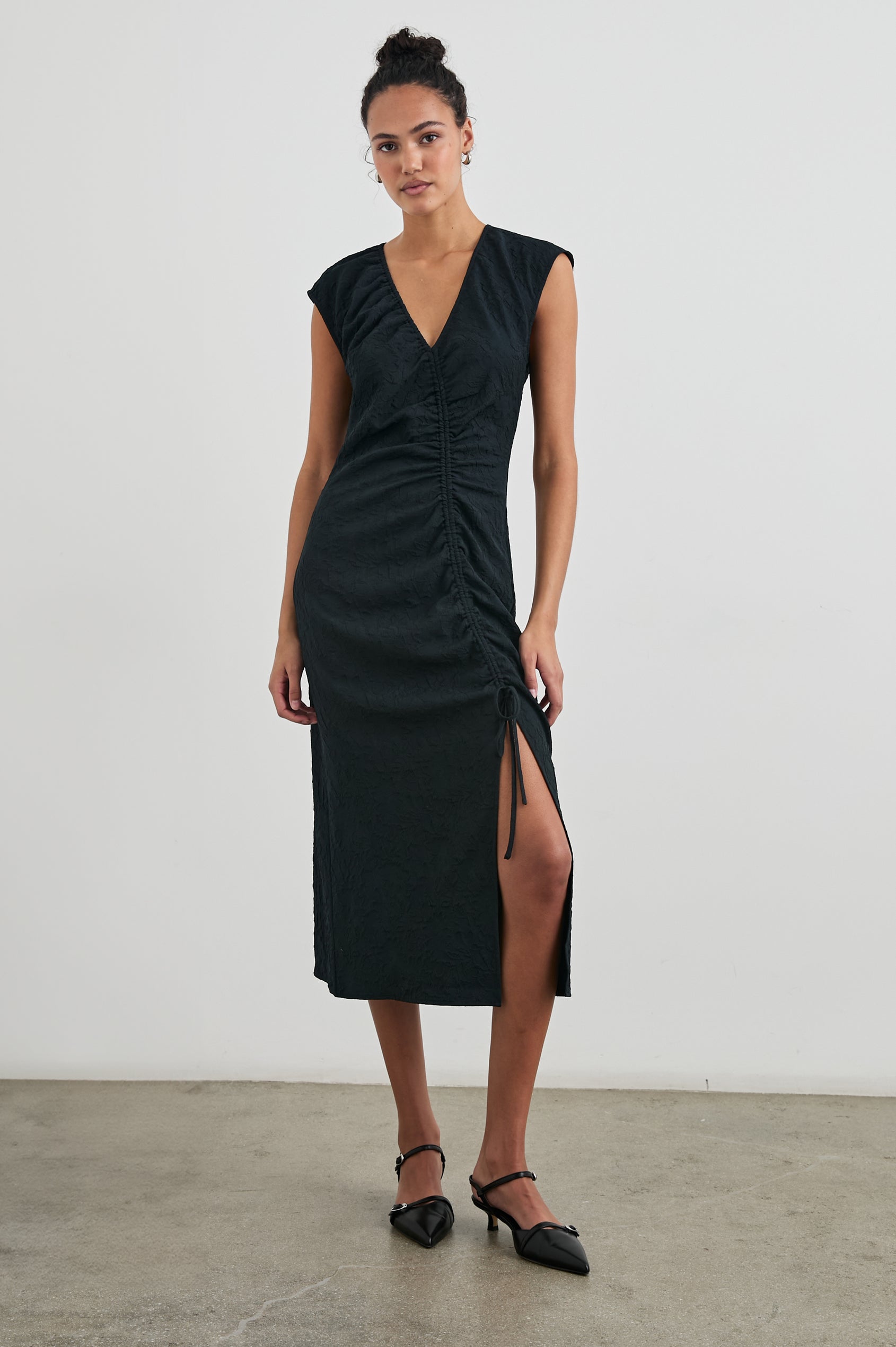 Auren Midi Dress with Cap Sleeves, a Deep V Neck, a Mid-Thigh Side Slit and Ruching from the V Neck to the Slit with a Drawcord at the Slit in Black Jacquard Colorway - Front Full Body View Featured on Model 