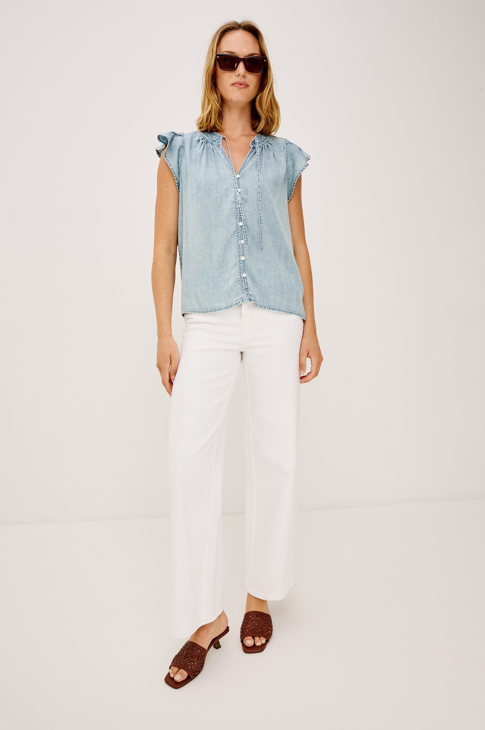Aviva Top in TENCEL™ Denim With Smocked Flutter Sleeves, Split V-Neck With Embroidered Collar and Self-Ties, and Front Buttons in Bleached Indigo Colorway - Upper Body Front View Featured on Model