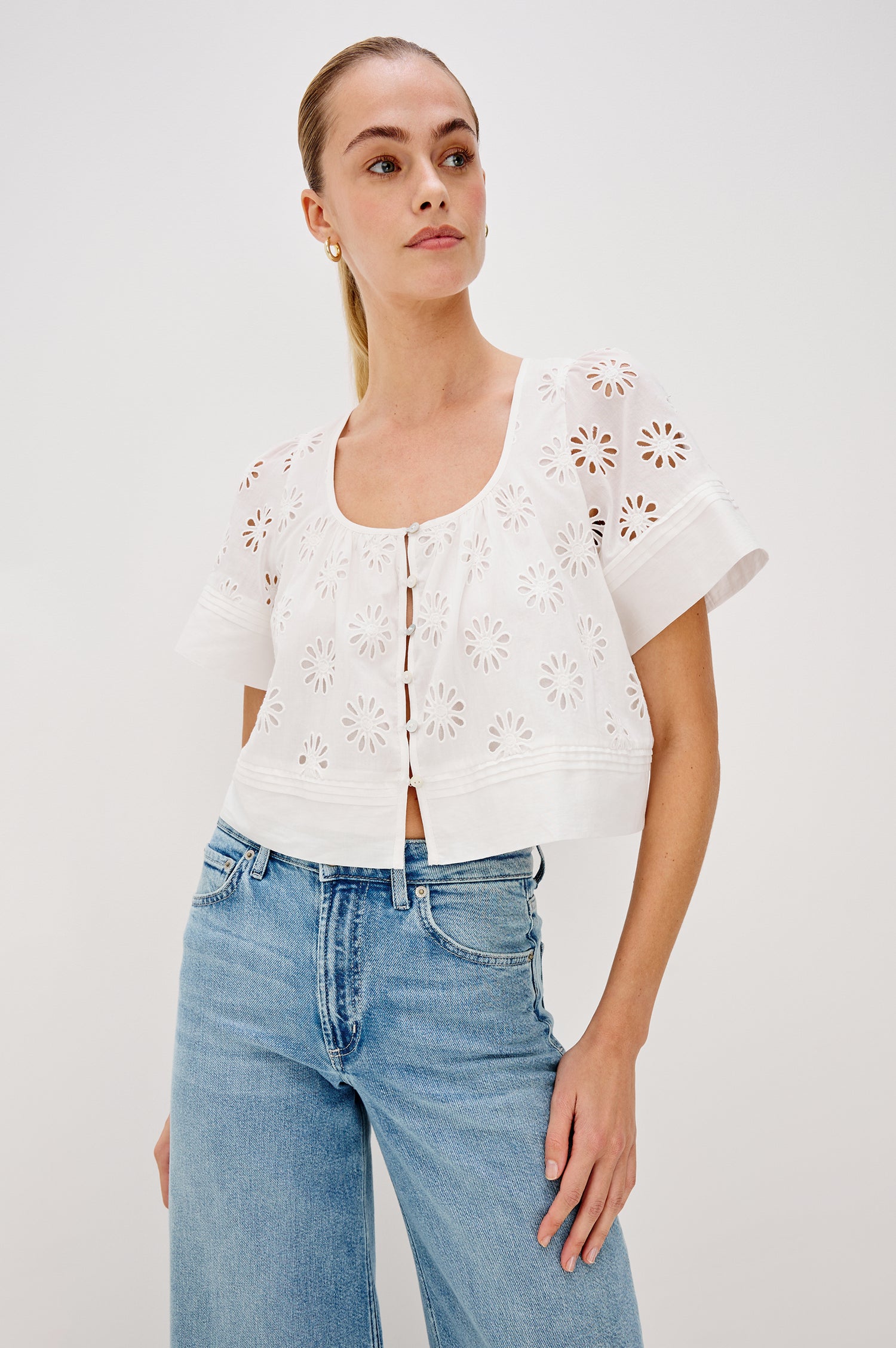 Bambina scoop neck top with short sleeves, button front, baby doll shape with cutout flowers through out in White colorway. Front View Shown on Model.