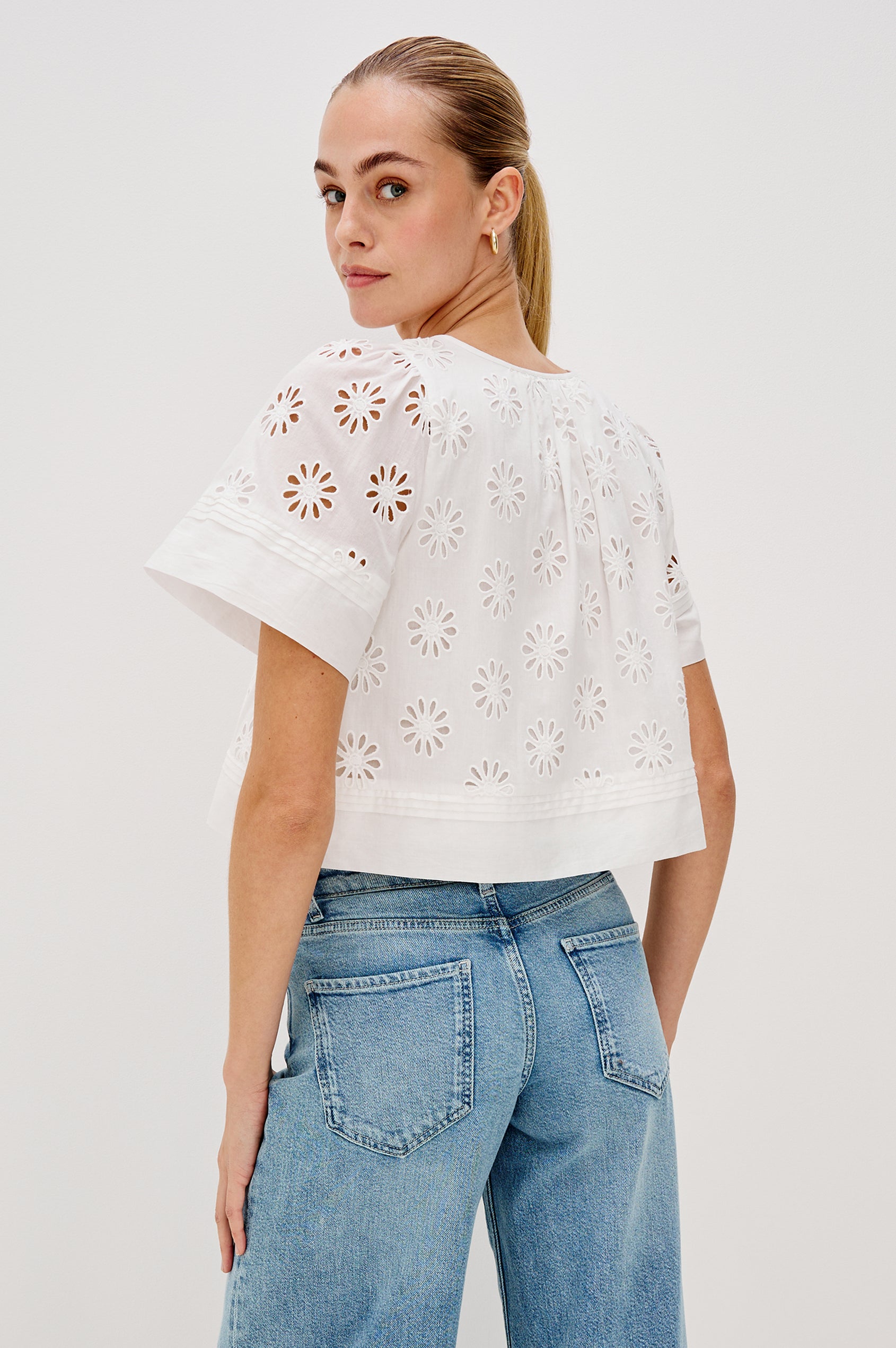 Bambina scoop neck top with short sleeves, button front, baby doll shape with cutout flowers through out in White colorway. Back View Shown on Model.