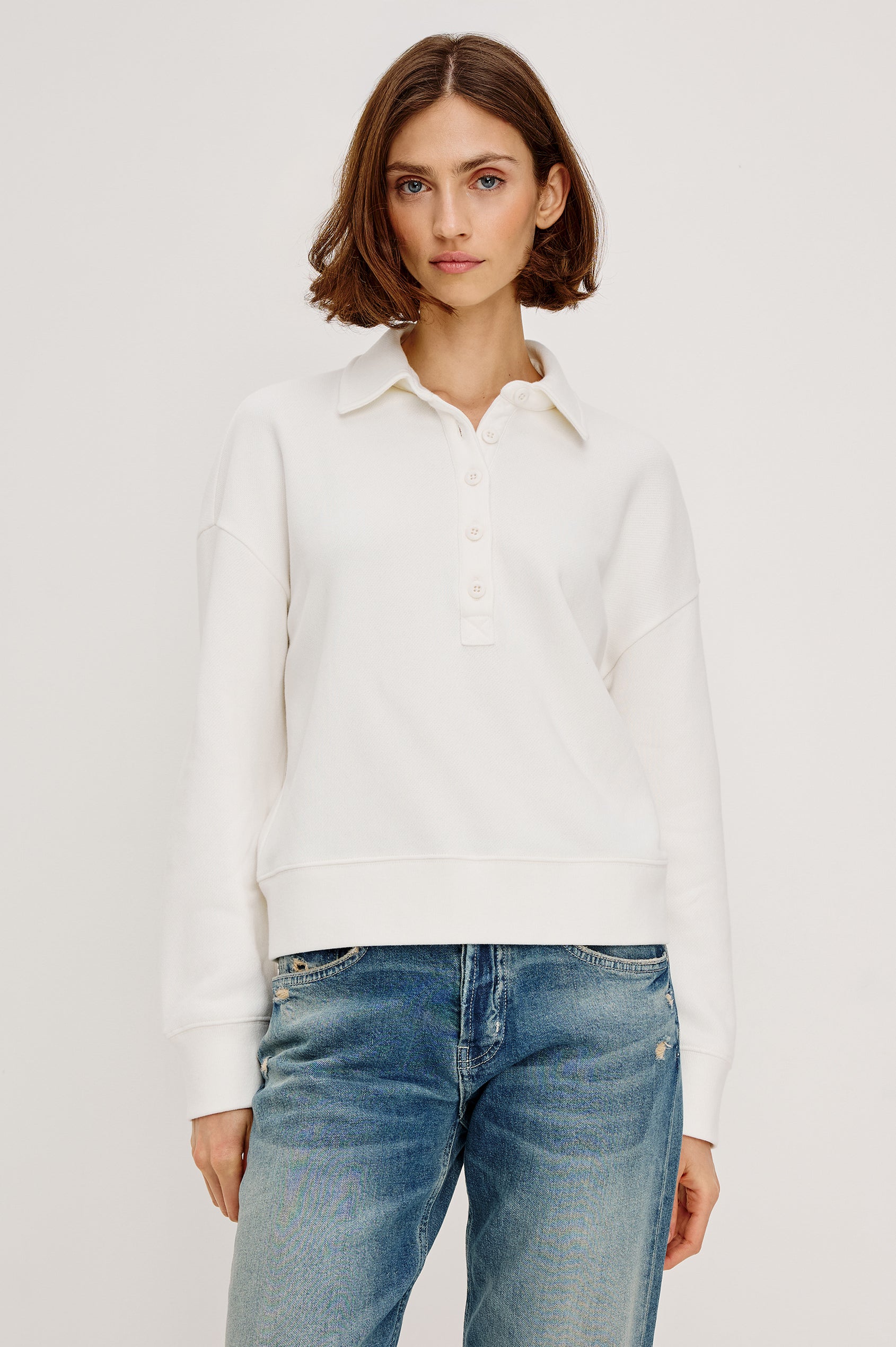 Cotton polo-style sweatshirt made from French terry fabric. The design features a button-front half placket, drop shoulders, and binding at the hem and cuffs for a relaxed, comfortable fit in Ivory Colorway - Front view featured on model
