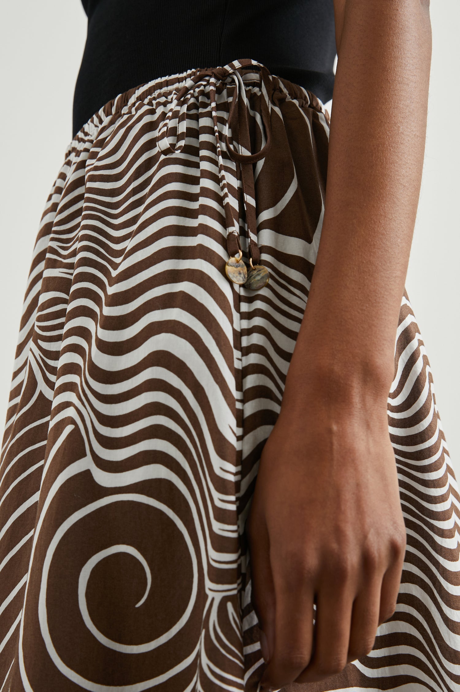 Beech Midi Skirt with a Side Drawstring Waist in Swirls Colorway, White Waves and Swirls on Brown - Side View Featured on Model 