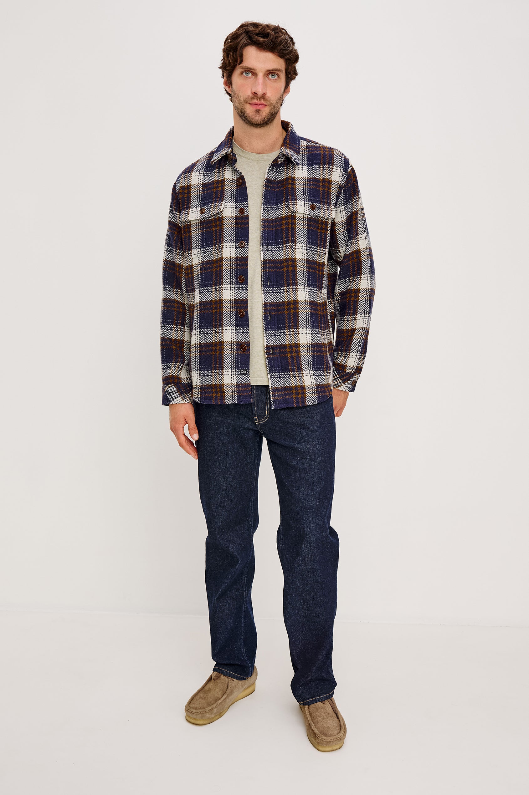 The Berkshire is a plaid shirt jacket with two chest pockets button front and collar in Navy Umber Cream colorway. Front full body view featured on model.
