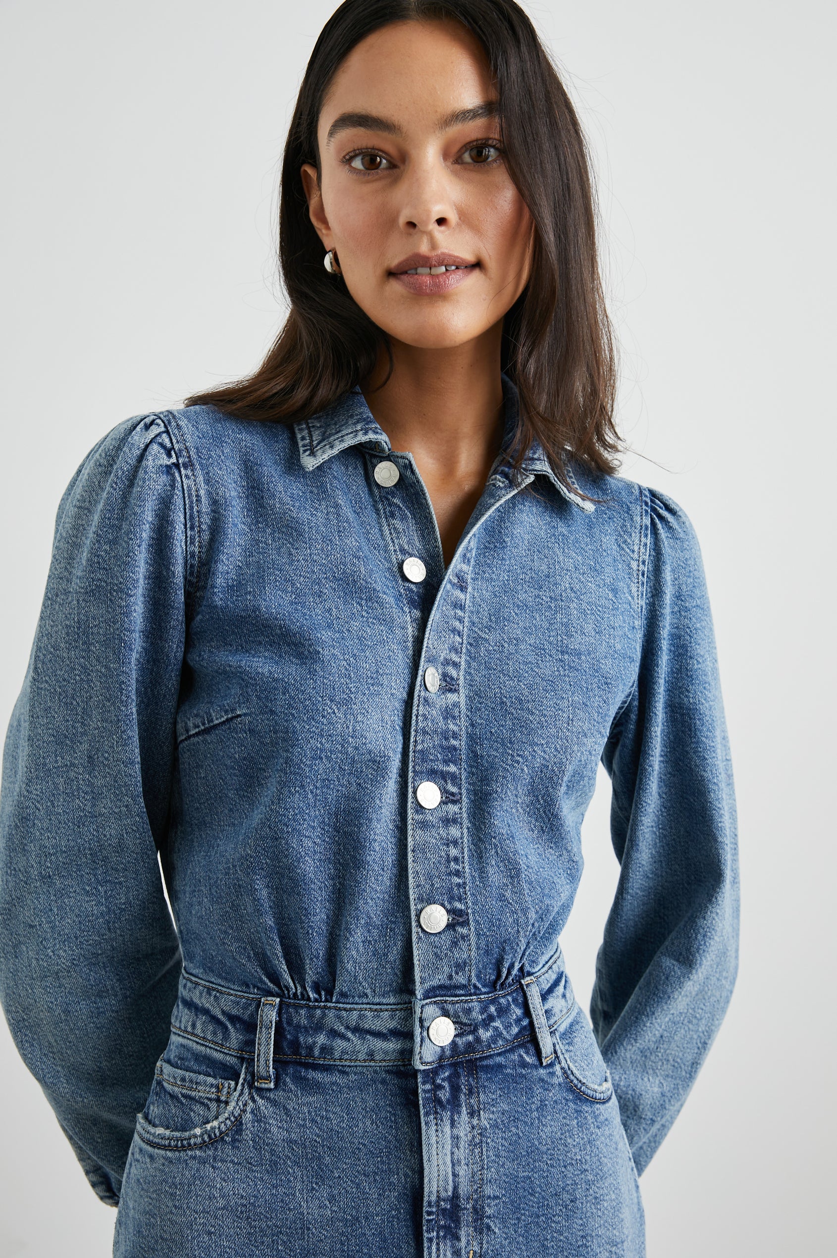 Beverly Long Sleeve Denim Knee Dress with a Back Vent, Belt Loops, a Button and Zipper Closure for the Skirt and Button Closure on the Bodice, a Collar, two Front Pockets plus a Coin Pocket and Two Back Patch Pockets in West Coast Colorway, a Blue - Front View Featured on Model