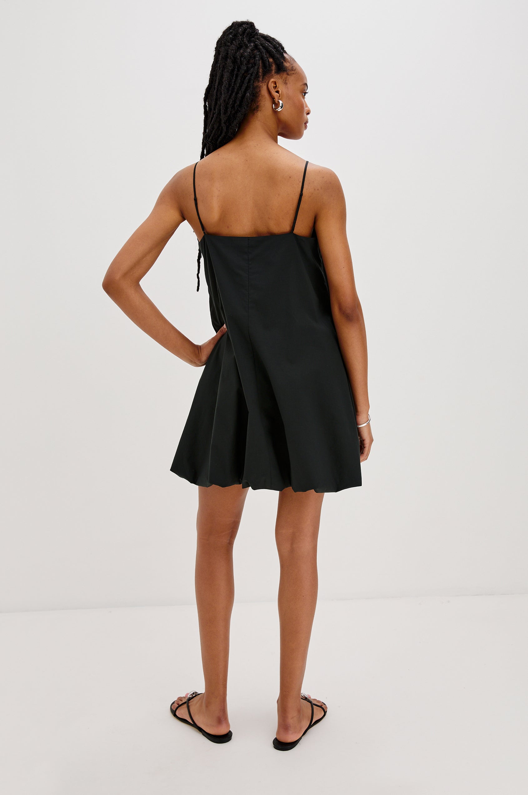 Blanca Bubble Hem Mini Dress with Spaghetti Straps and Side Pockets. Full Body Back View Shown on Model.