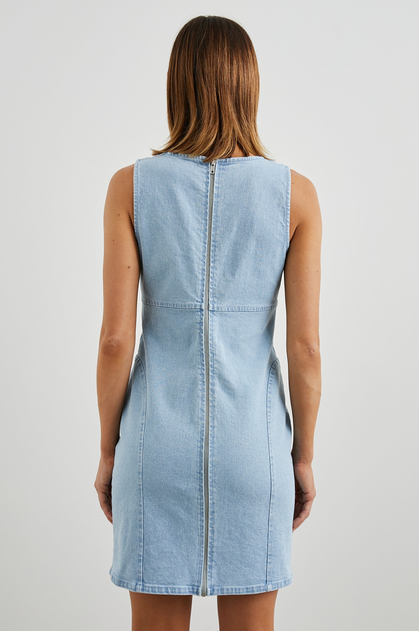 Blaze Denim Sleeveless Mini Dress with a Scoop Neck, Wide Shoulder Straps, a Full Zipper Back Closure, and Additional Seams in Bleach Indigo Colorway - Back View Featured on Model 