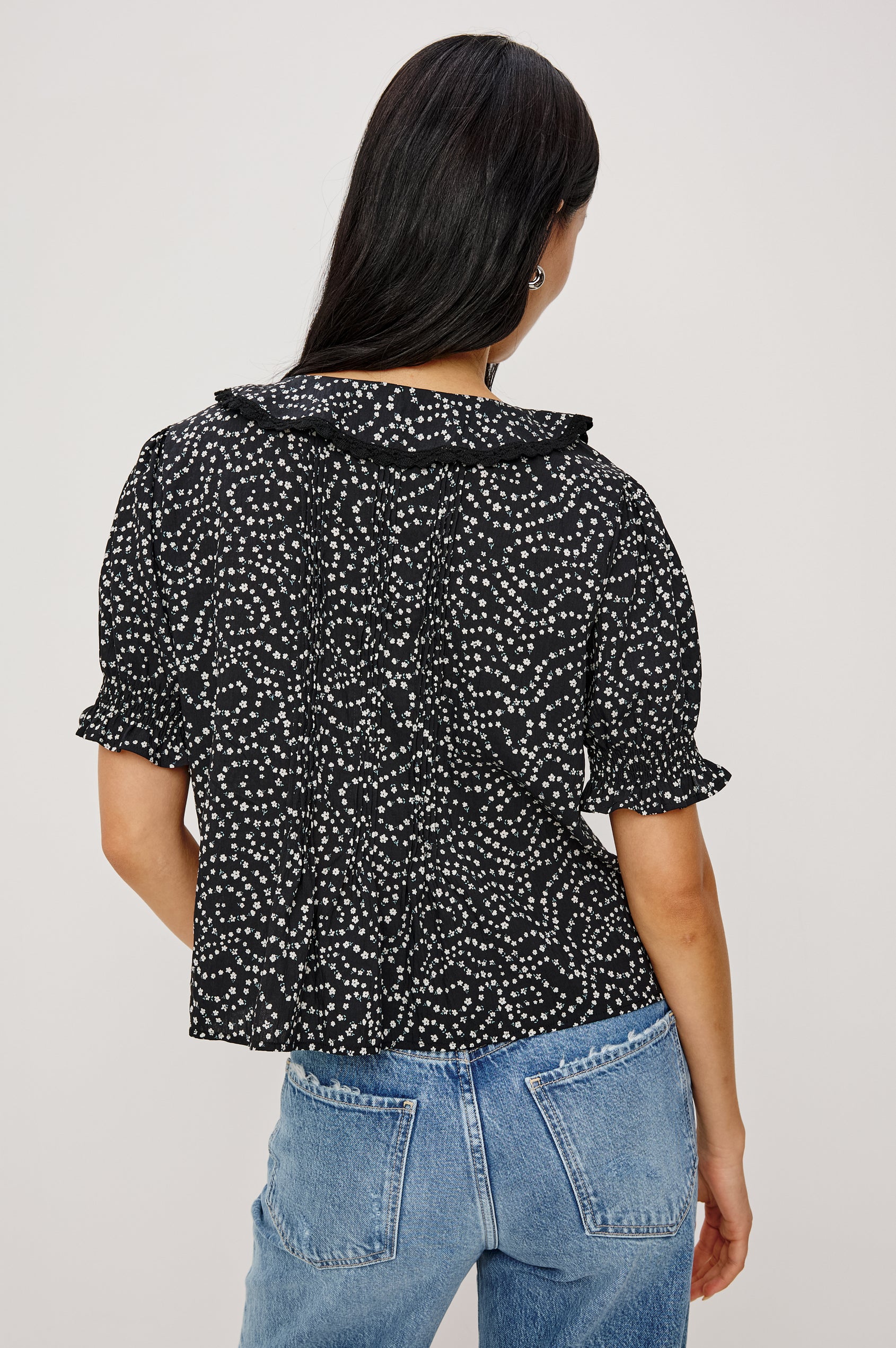 Bloom Poplin Top With Ruffle V-Neckline, Elbow-Length Puff Sleeves With Ruffled Cuffs, Pintuck Detailing, and Boxy Relaxed Fit in Mini Chain Daisies Colorway - Upper Body Front View Featured on Model