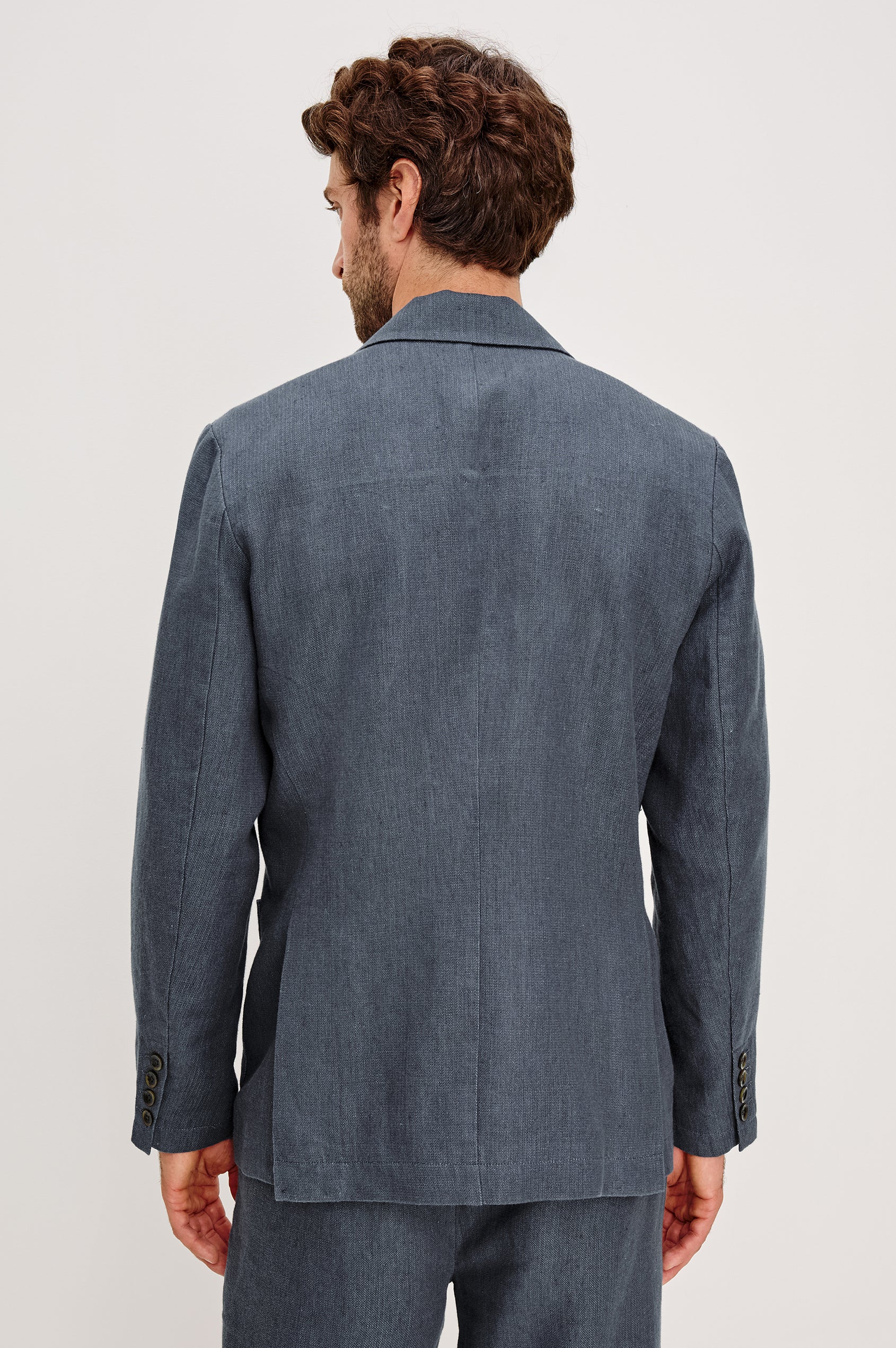 The Bond is a single breasted blazer with two buttons, one chest pocket and two patch pockets in a blue Meridian colorway. Back view featured on model.