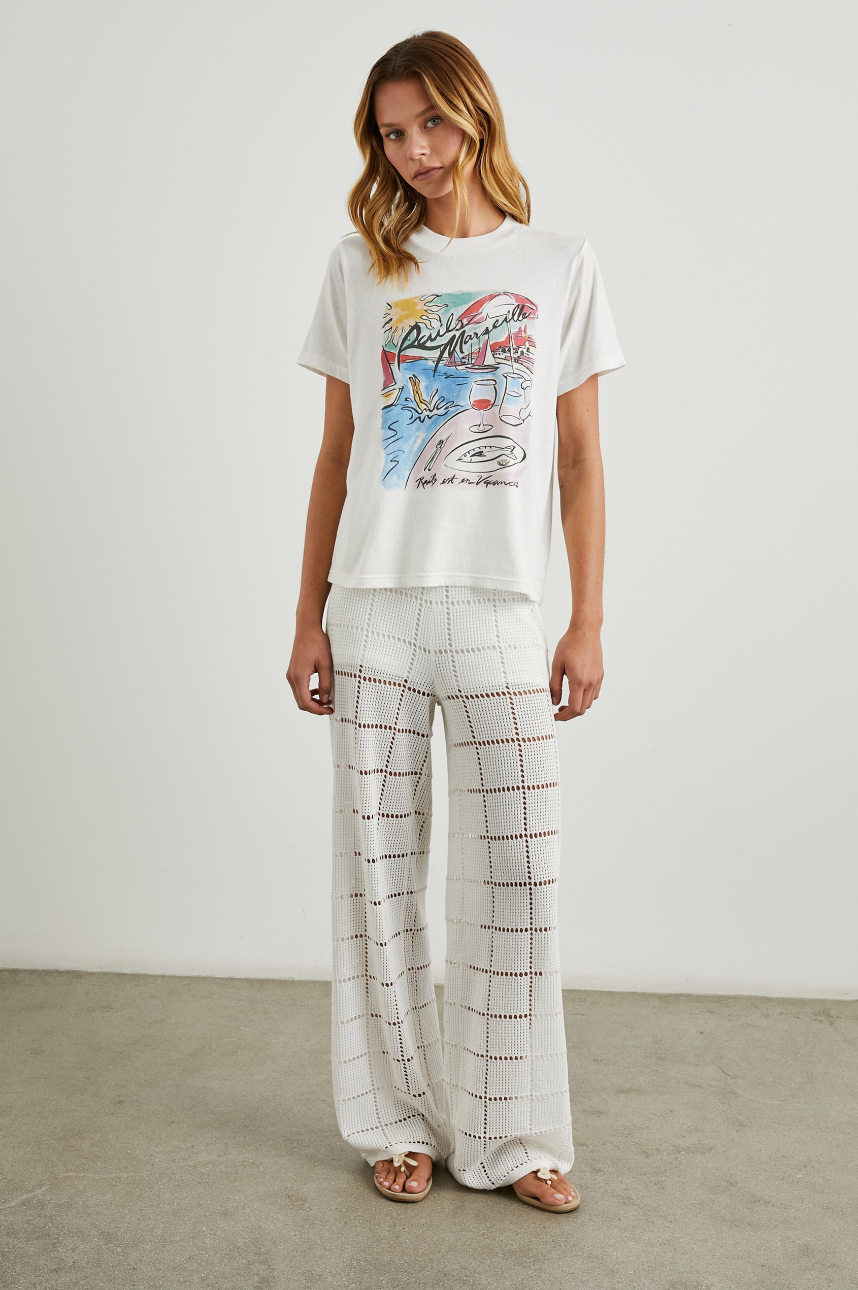 Boyfriend T-Shirt with a Crew Neck, a seaside image and the text, Rails Marseille Rails et en Vacances in Rails Marseille Colorway, with text and image in black and pinks on a White shirt - Front Full Body View Featured on Model