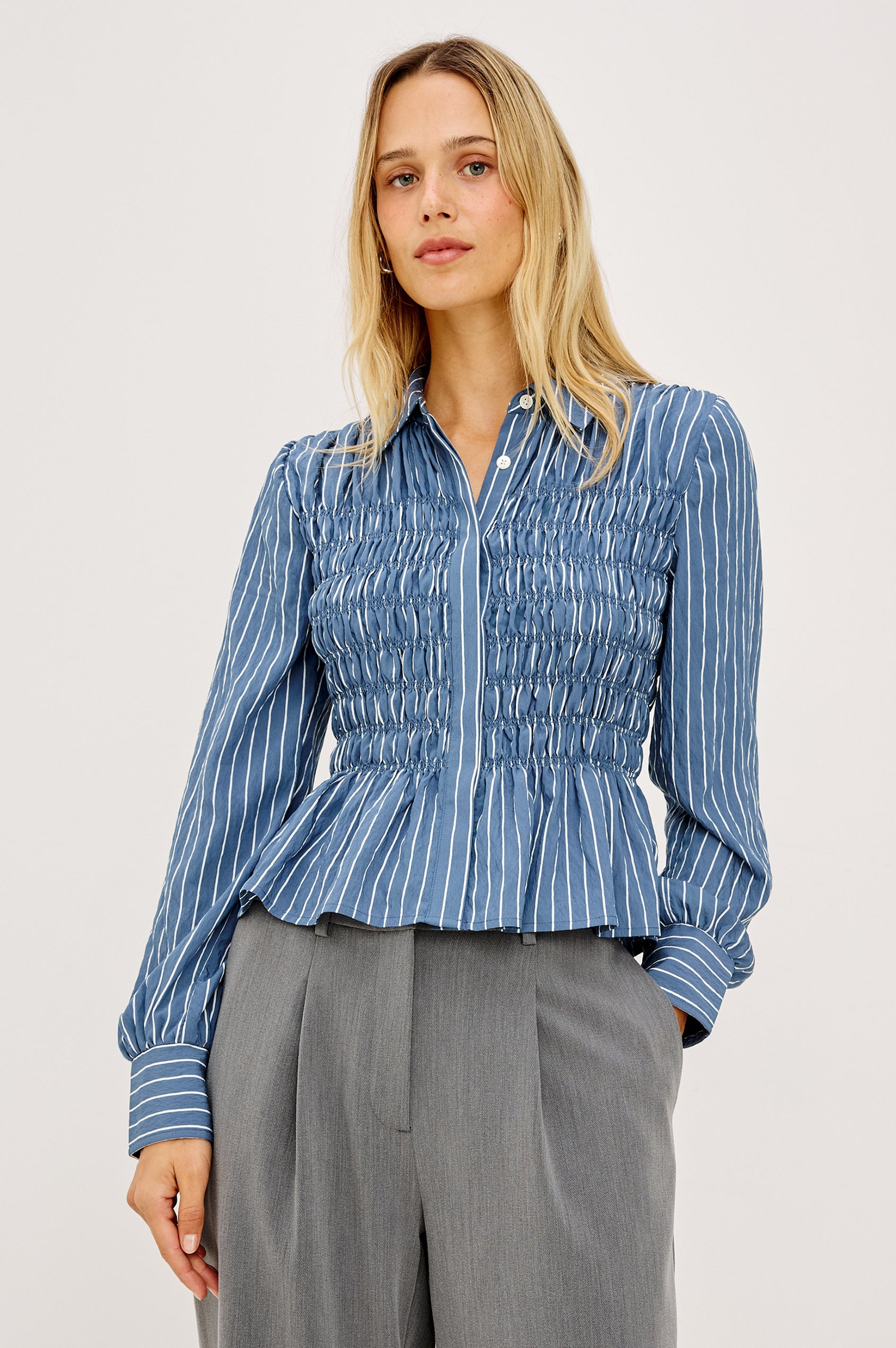 Bradshaw Shirt in Cotton Poplin With Button-Up Front, Collar, Smocked Body, Peplum Hem, and Bishop Sleeves in Washed Indigo Stripe Colorway - Upper Body Front View Featured on Model