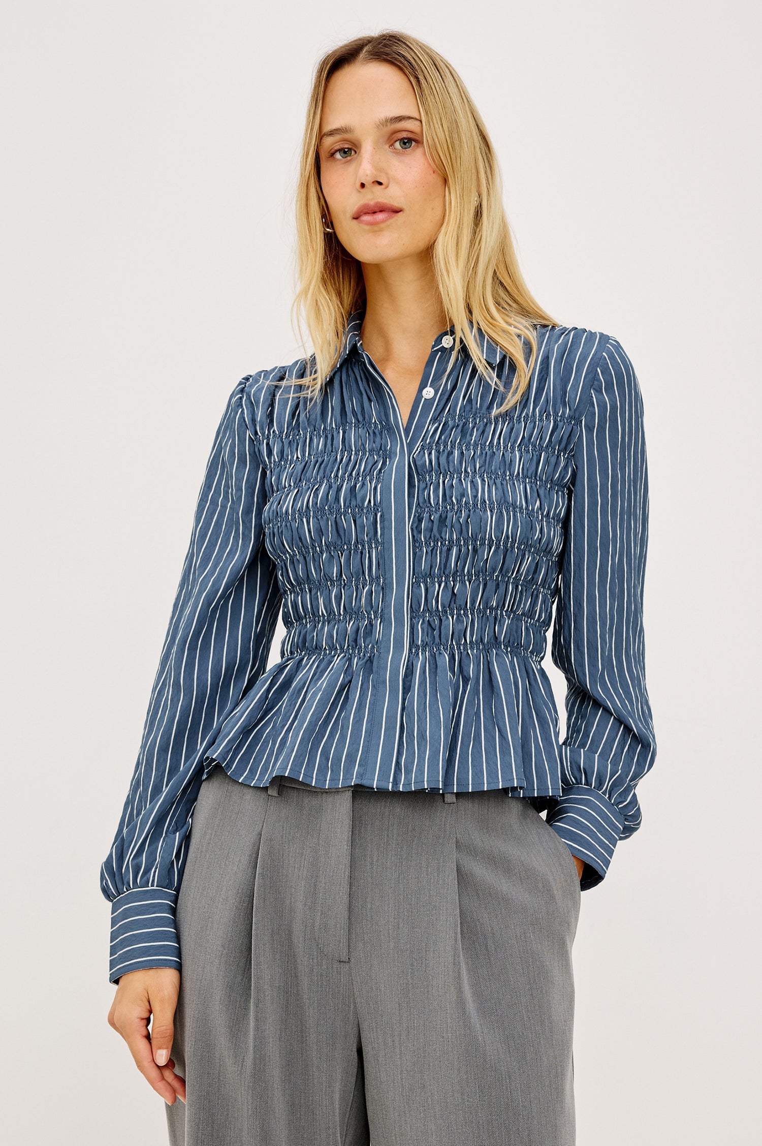 Bradshaw Shirt in Cotton Poplin With Button-Up Front, Collar, Smocked Body, Peplum Hem, and Bishop Sleeves in Washed Indigo Stripe Colorway - Upper Body Front View Featured on Model