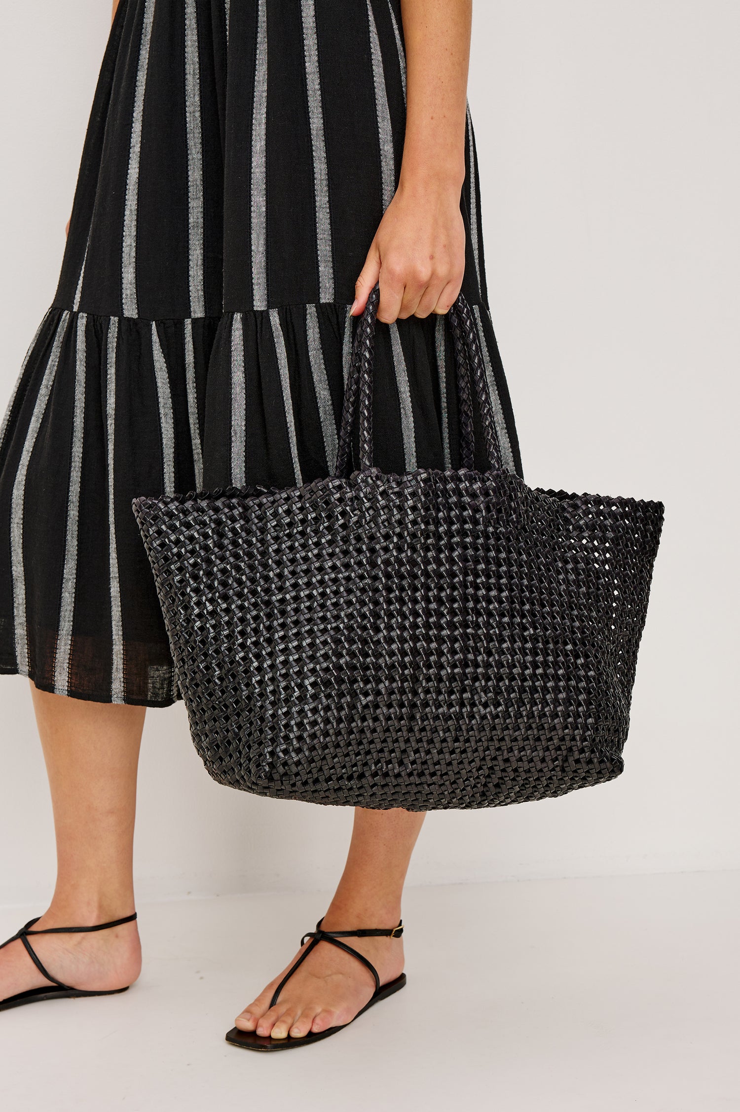 Brava oversized woven tote bag in Black - view of model holding bag at side