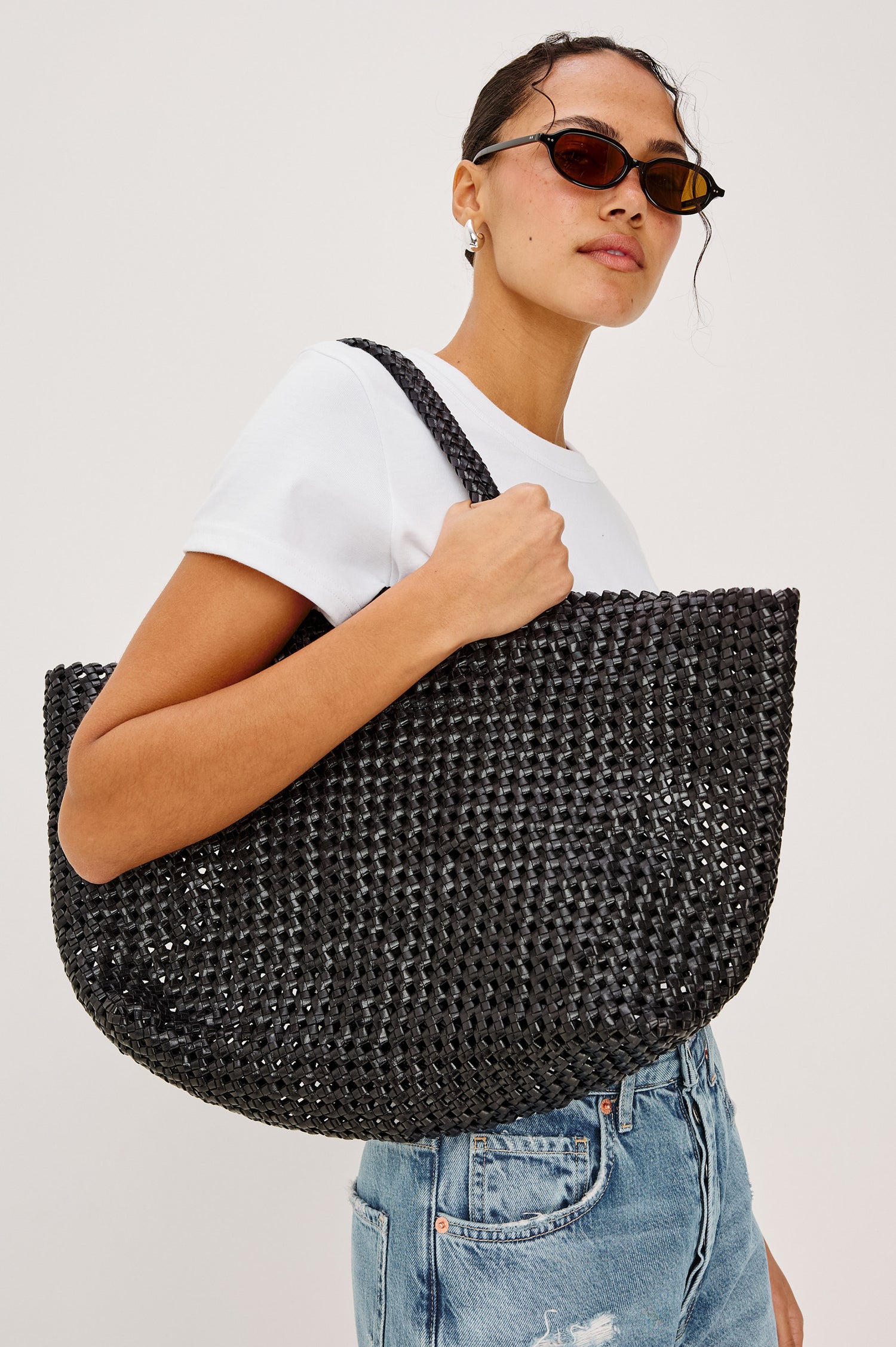 Brava oversized woven tote bag in Black - view of model holding bag on shoulder.