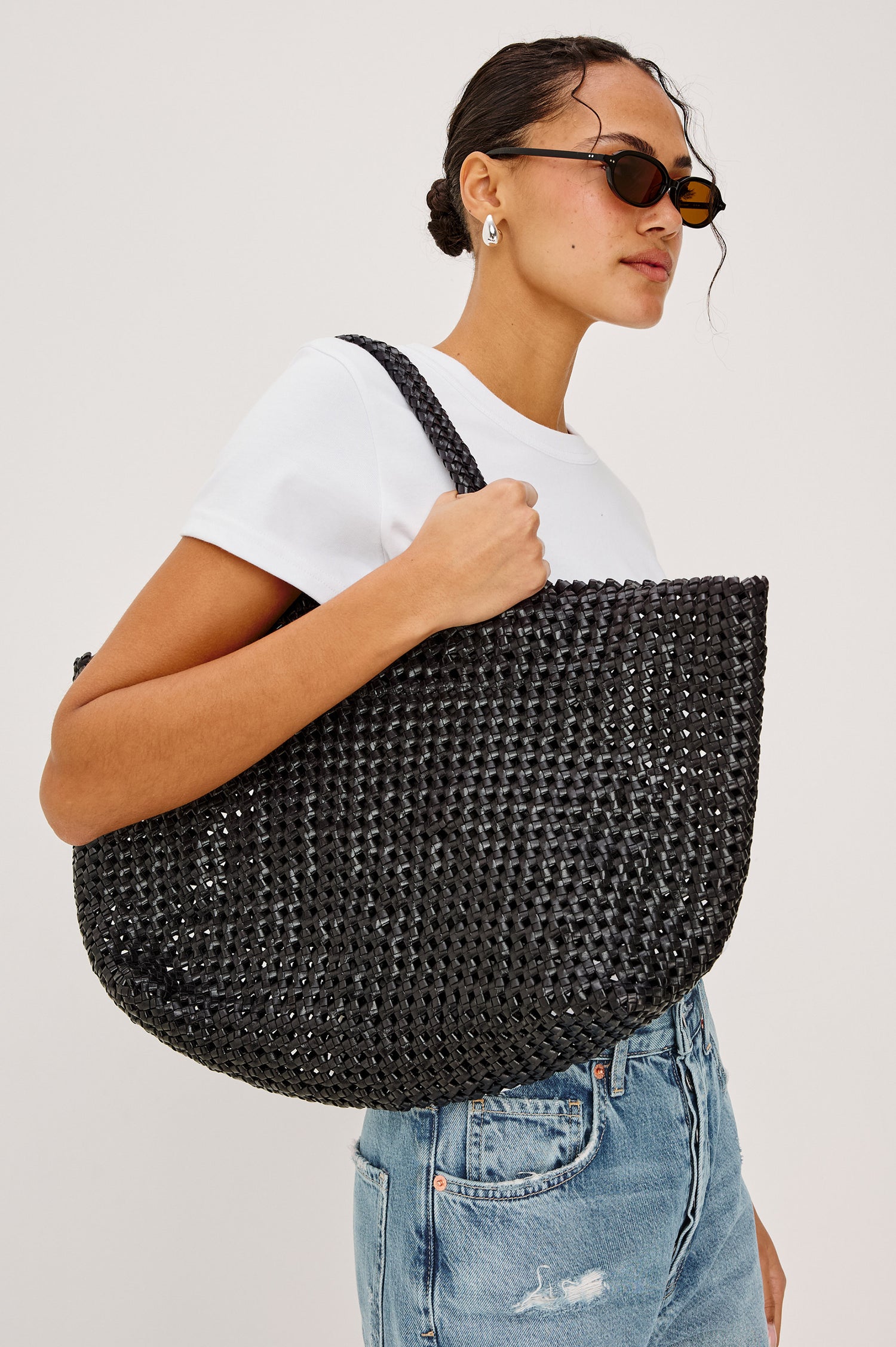 Brava oversized woven tote bag in Black - view of model holding bag at side on shoulder