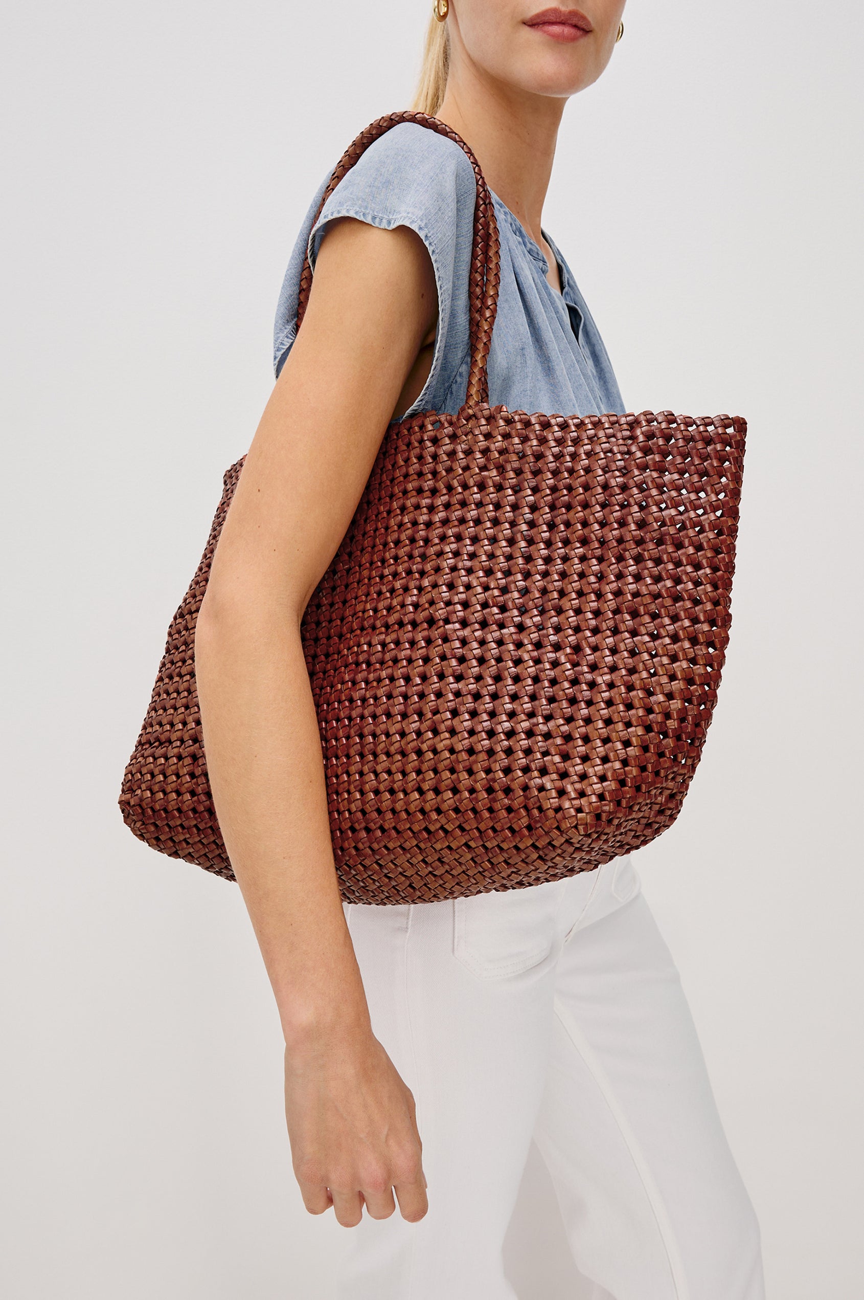 Brava oversized woven tote bag in Cognac brown - side view of model with bag over shoulder